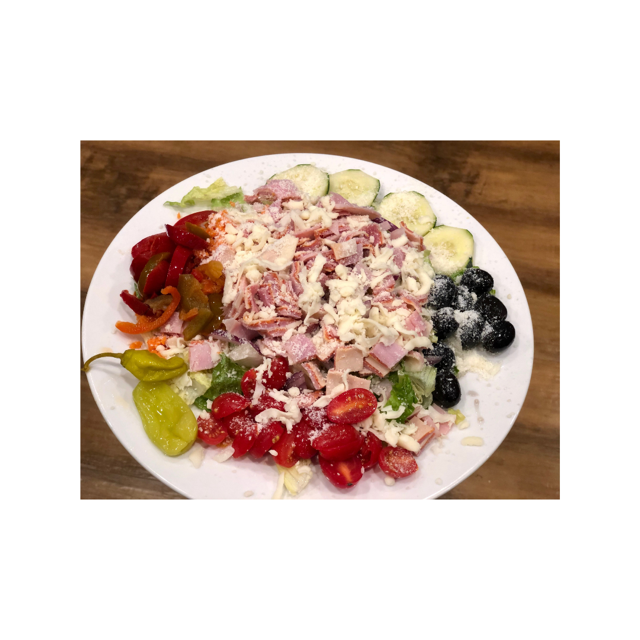 Antipasto salad on a white plate: ham, cheese, olives, tomatoes, cucumbers, peppers.
