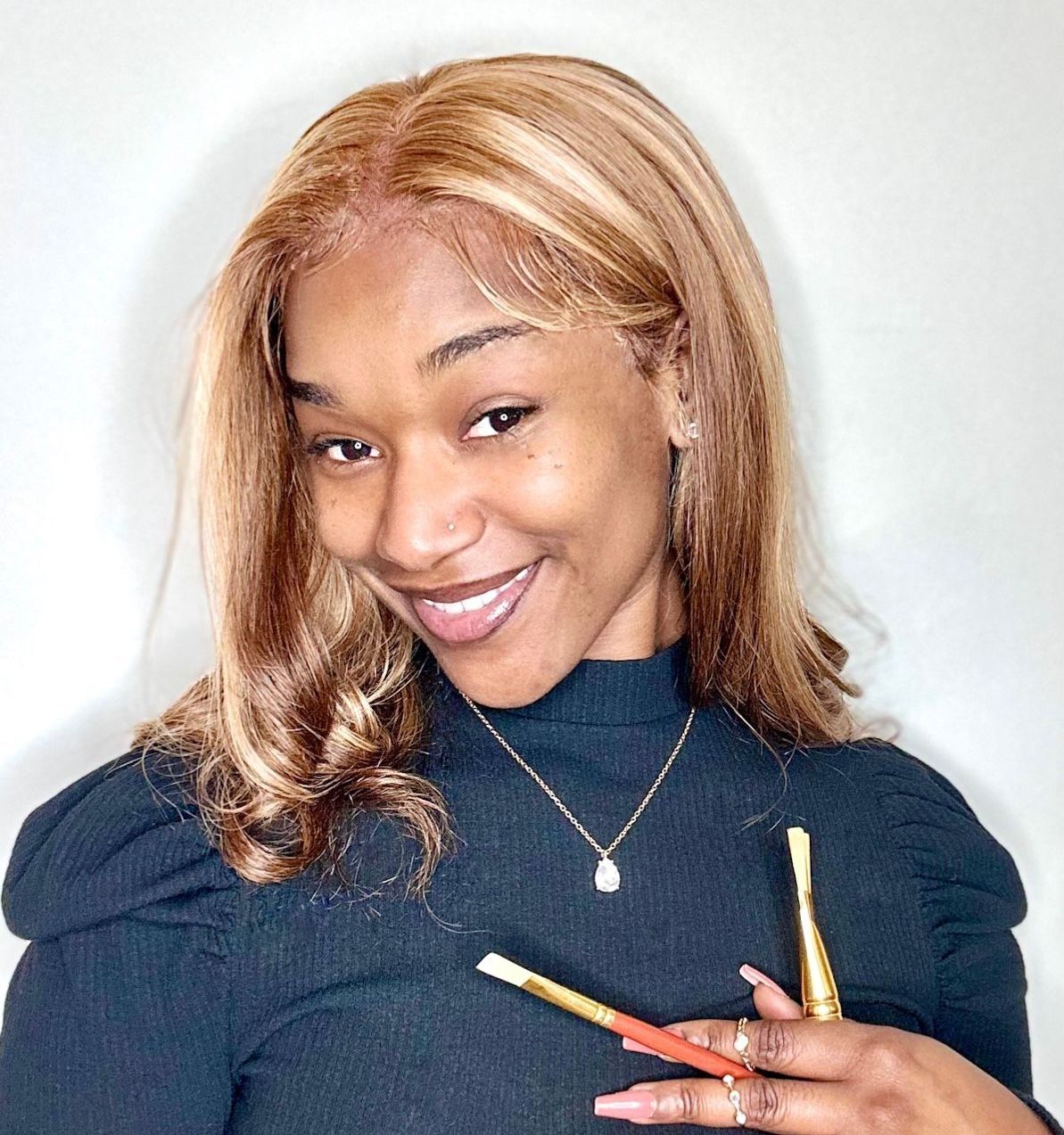 A woman is smiling while holding two brushes in her hands.