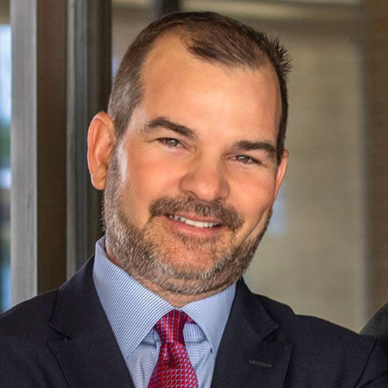 Laptop and tablet displaying financial charts on a wooden table.
