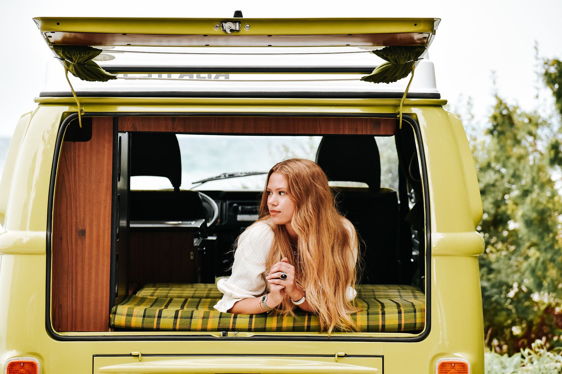 A man in a red shirt is leaning against a brick wall.