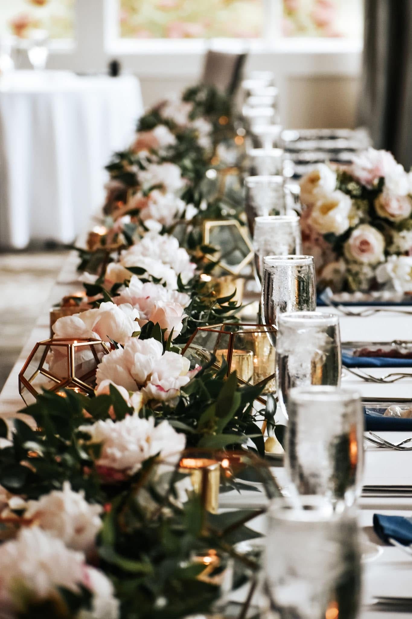 A long table decorated with flowers and candles for a wedding reception.