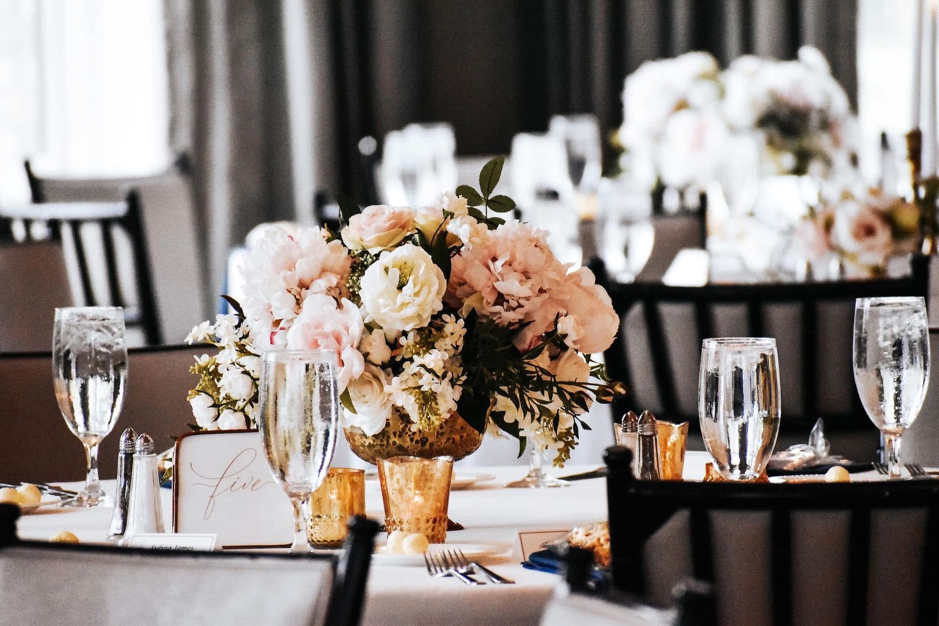 A table set for a wedding reception with a vase of flowers on it.