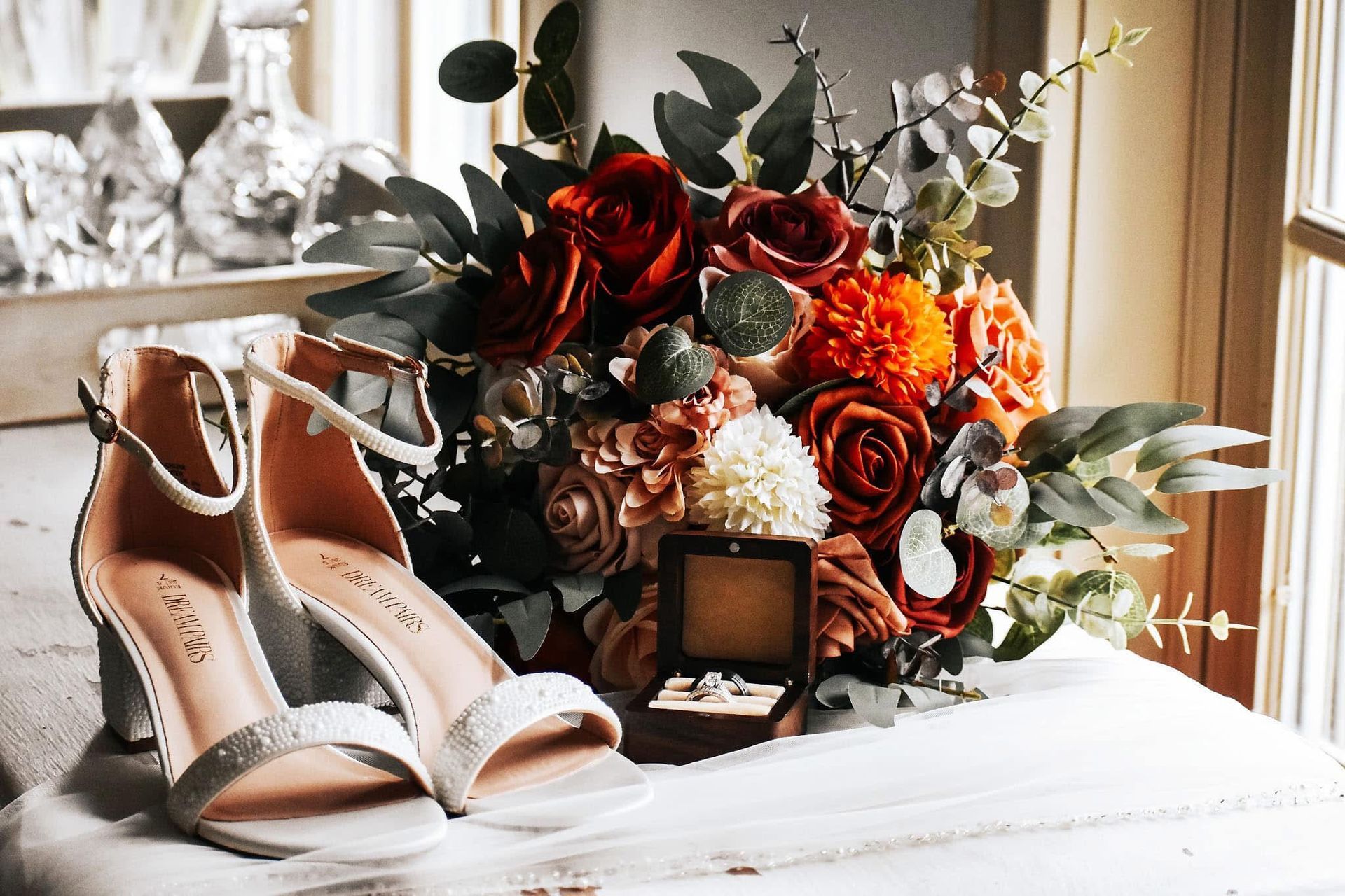 A pair of shoes and a bouquet of flowers are on a table.