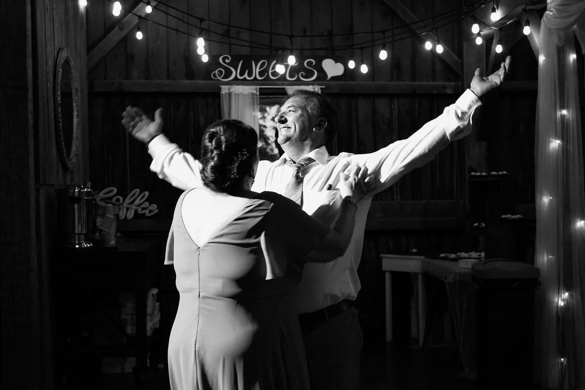 A black and white photo of a bride and groom dancing at their wedding reception.