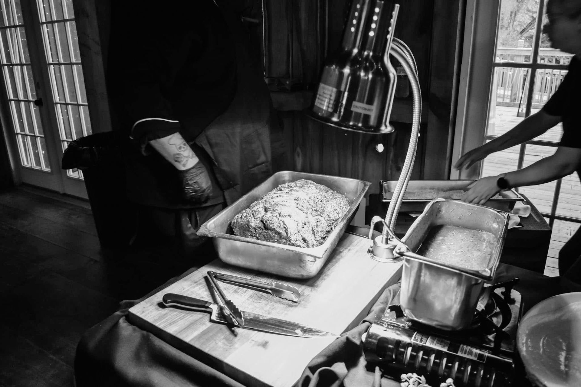 A black and white photo of a man preparing food on a table.