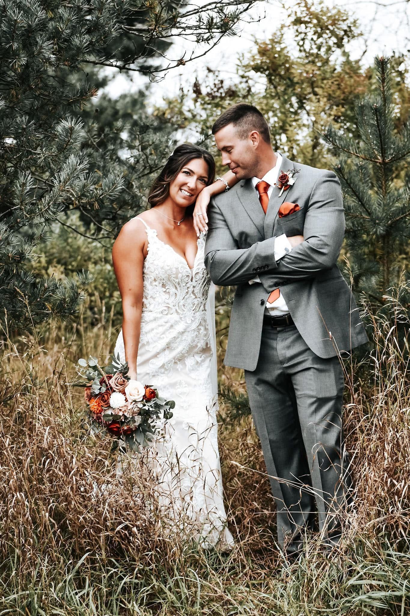 A bride and groom are posing for a picture in a field.