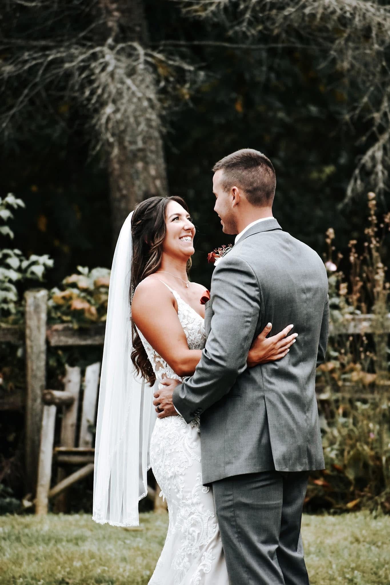 A bride and groom are dancing in the grass on their wedding day.