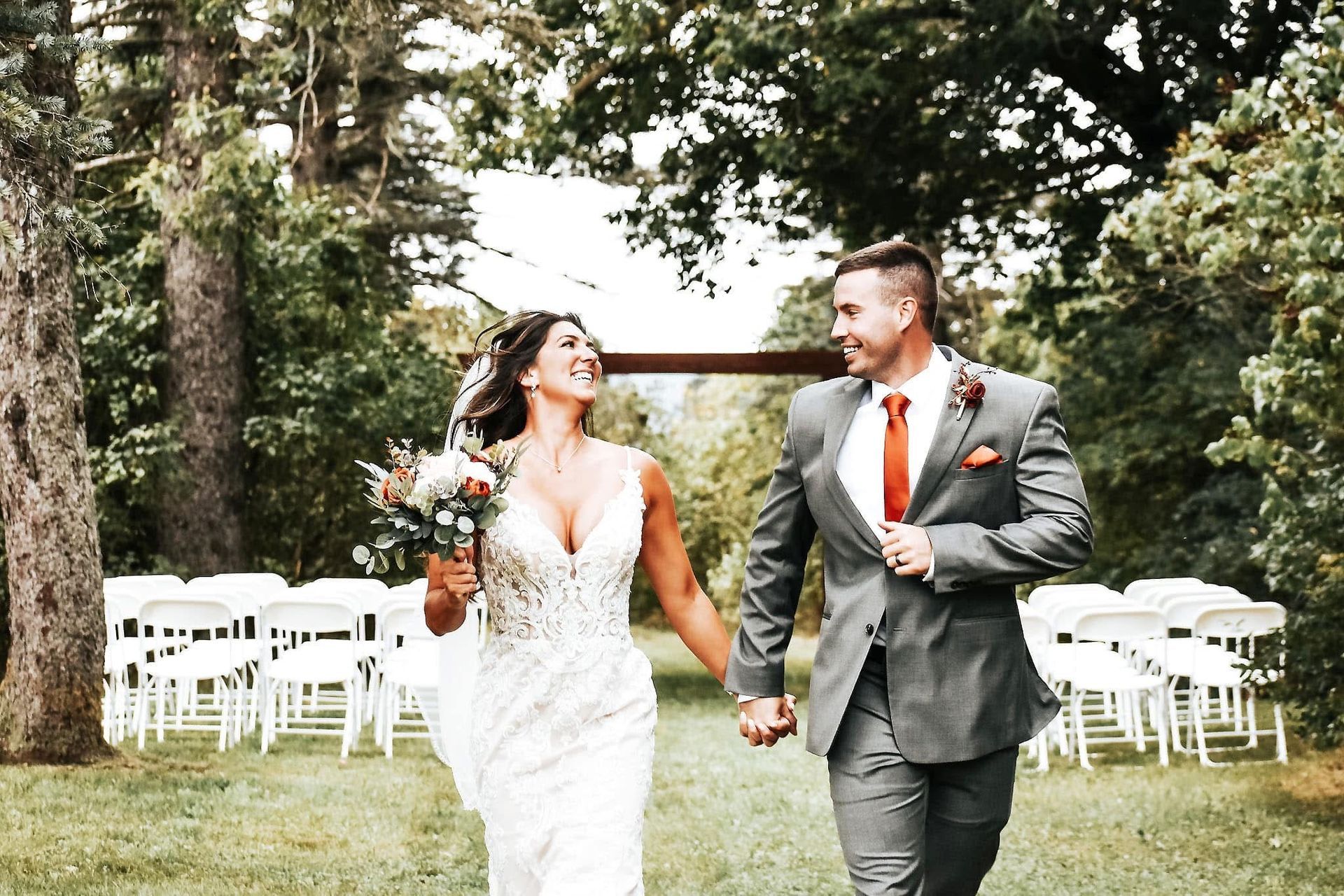 A bride and groom are walking down the aisle at their wedding holding hands.