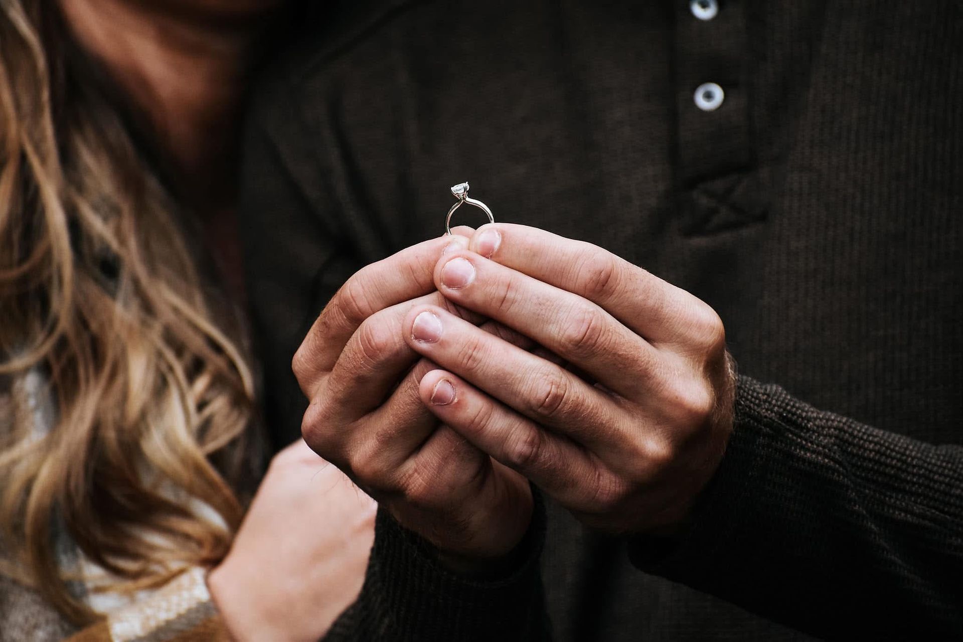 A man is holding an engagement ring in his hands.