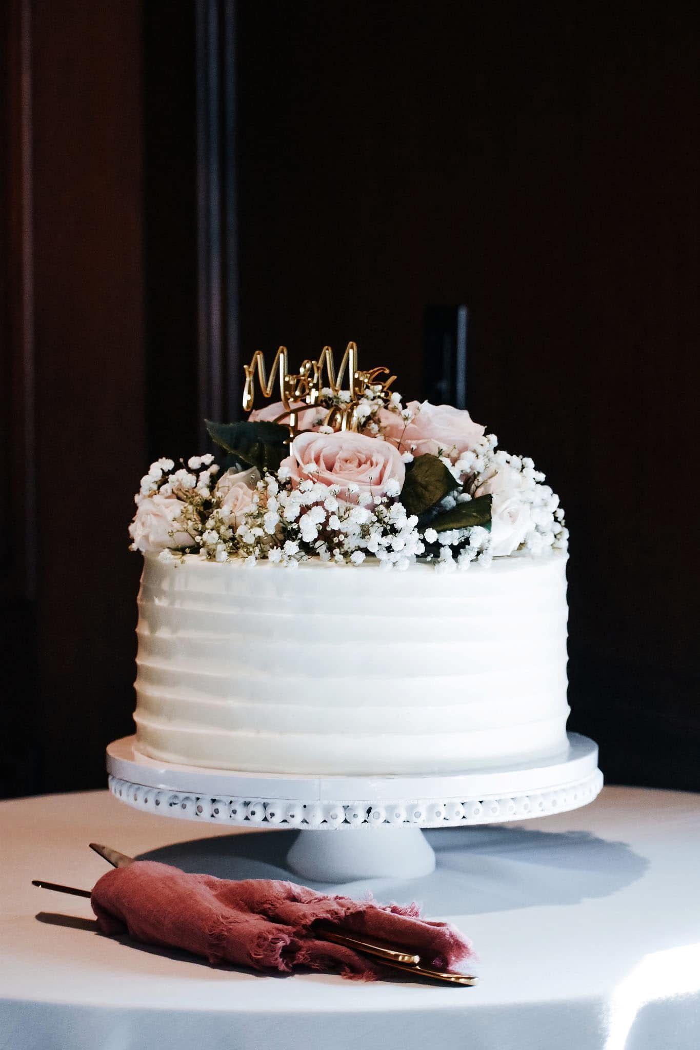 A wedding cake with flowers on top of it is on a table.