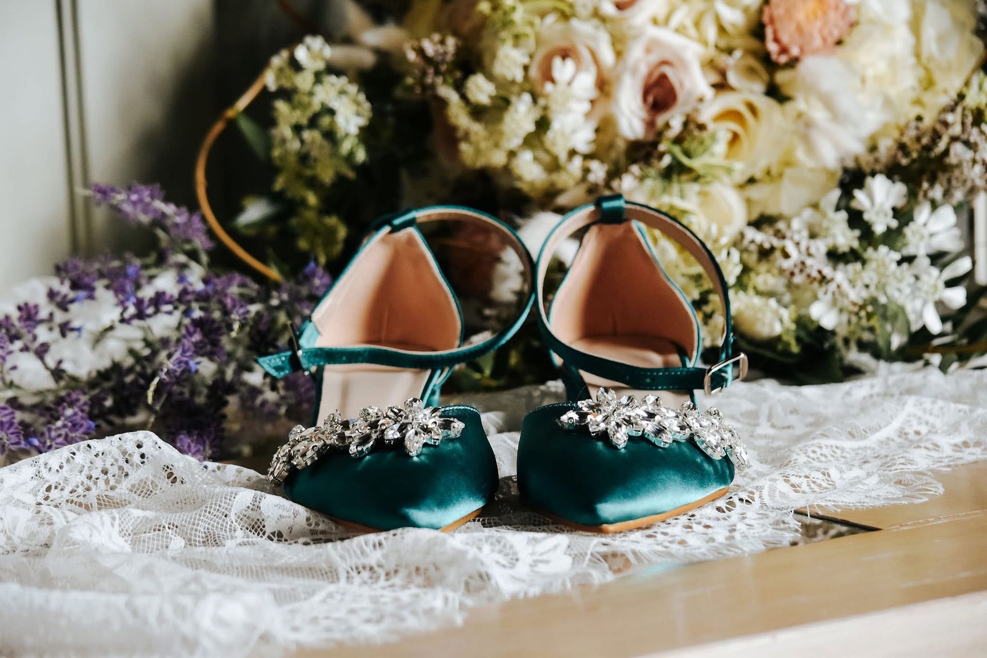 A pair of green shoes are sitting on a table next to a bouquet of flowers.