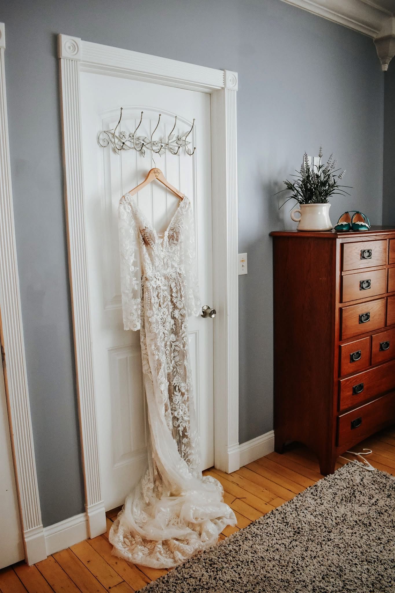A wedding dress is hanging on a door in a room.