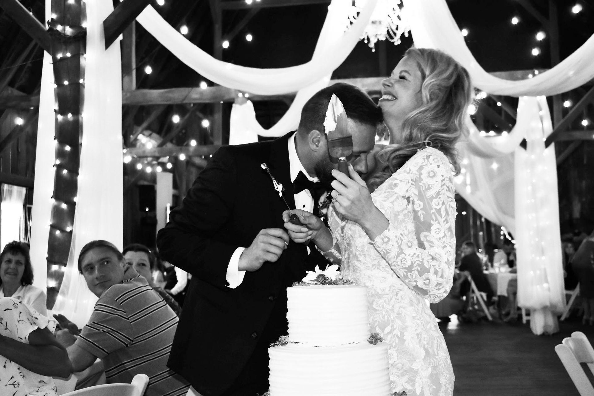 A bride and groom are kissing while cutting their wedding cake.