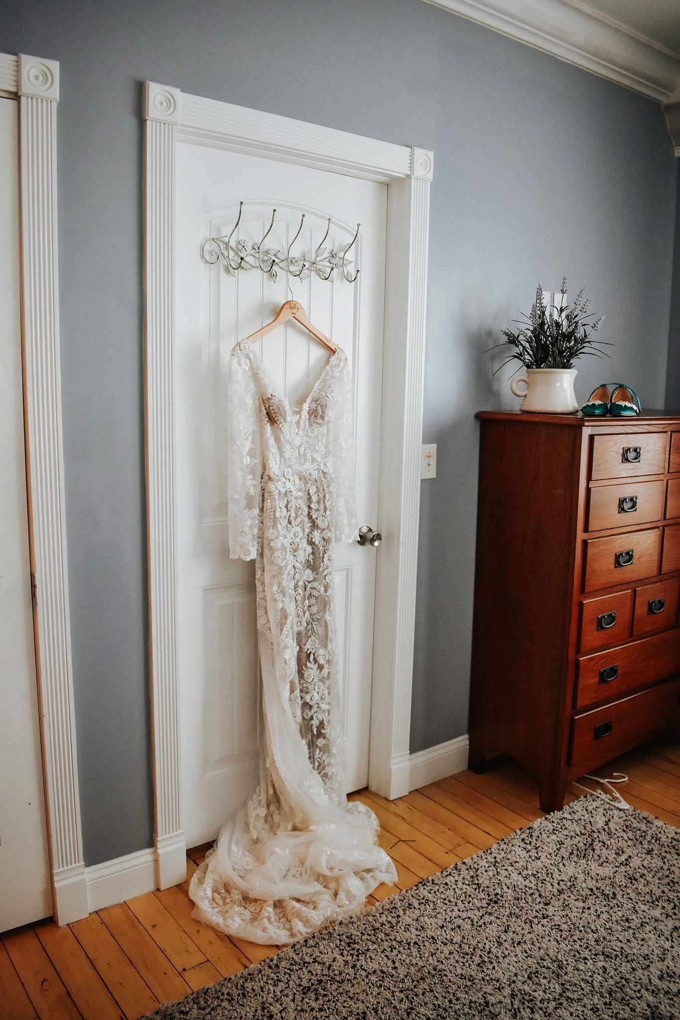A wedding dress is hanging on a door in a room.