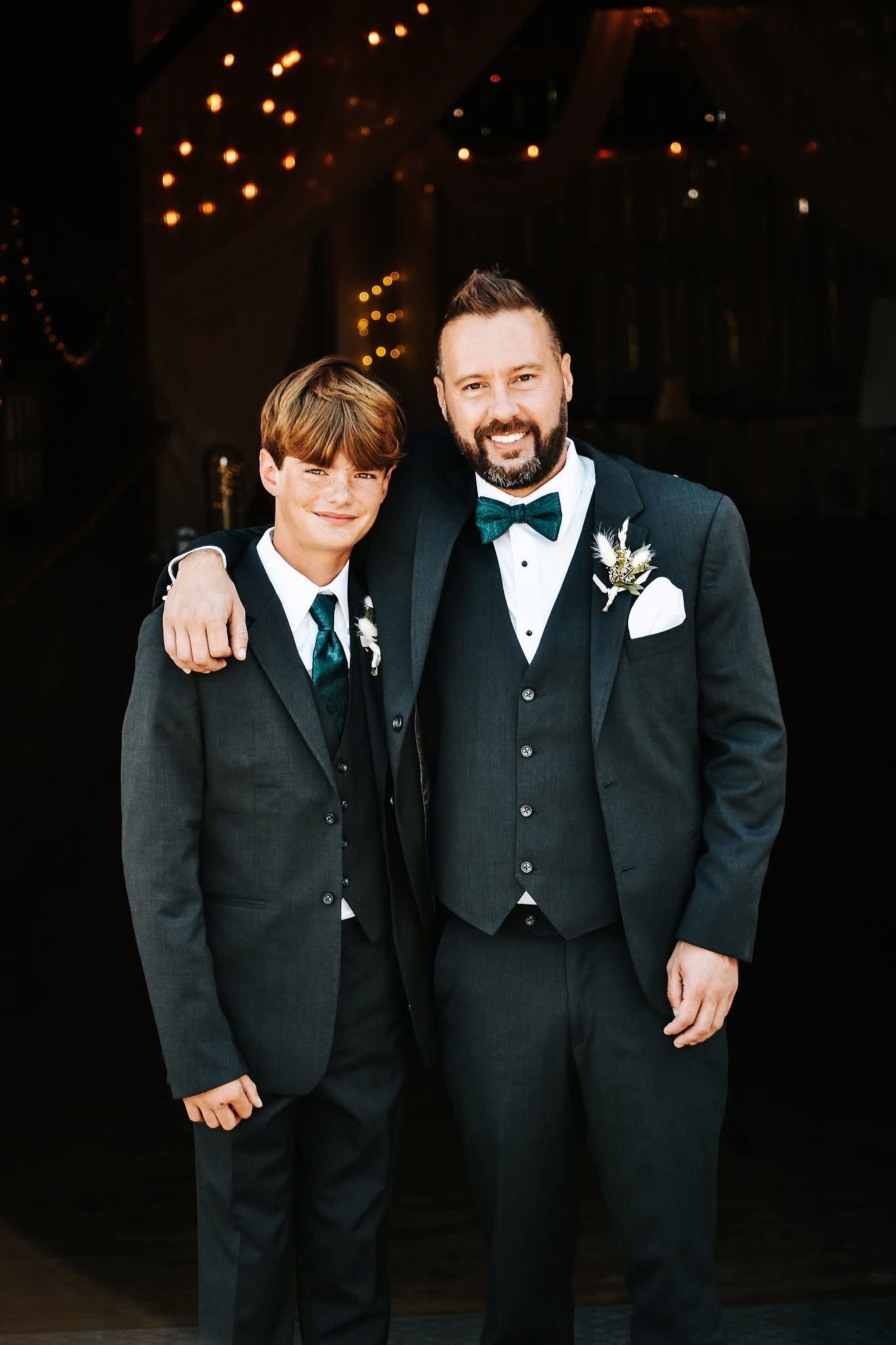 A man and a boy in suits are posing for a picture.