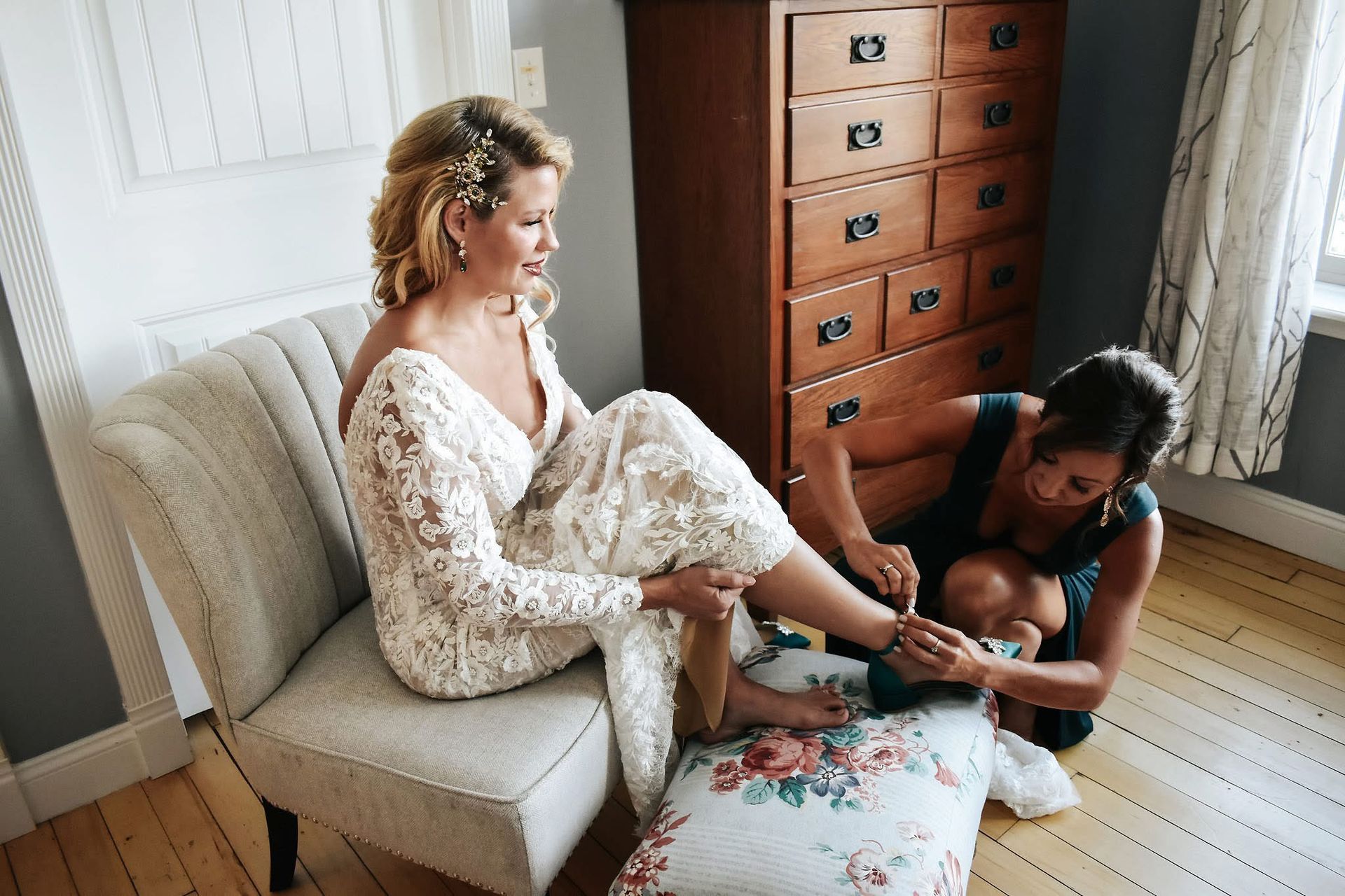 A bride is sitting in a chair while a woman paints her nails.