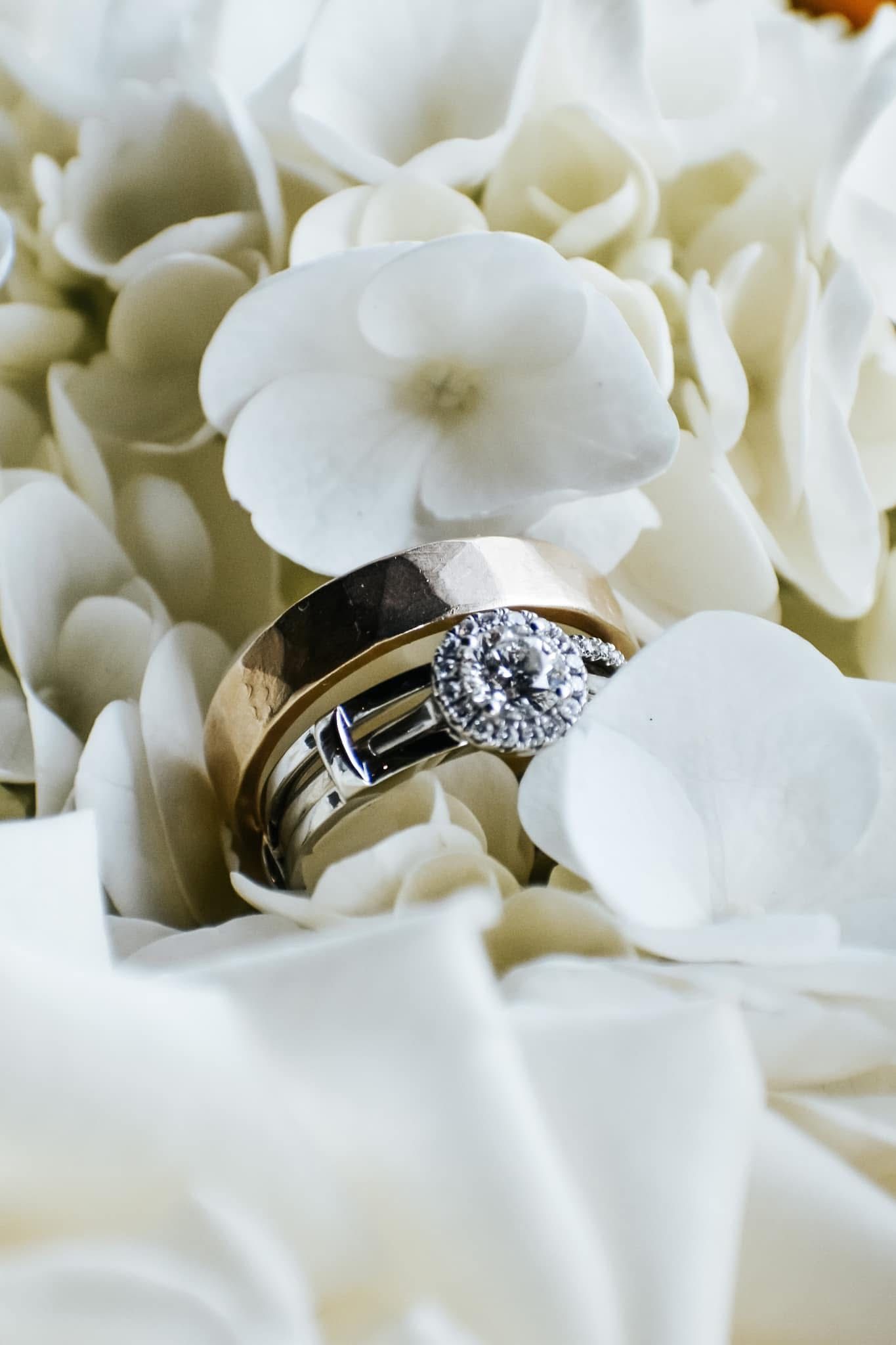 A couple of wedding rings sitting on top of a white flower.