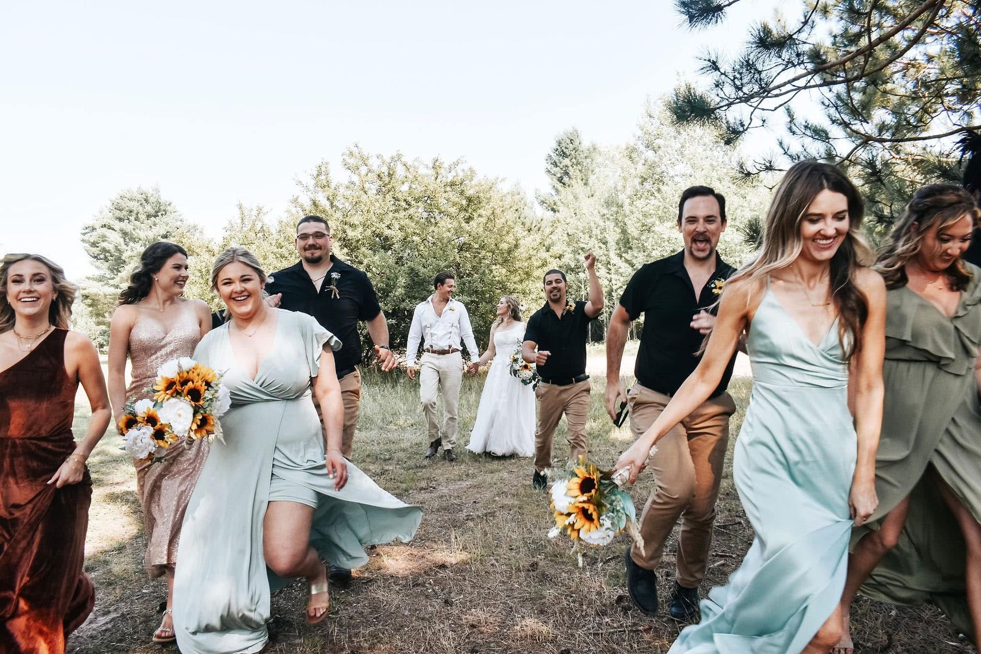 A bride and groom are walking with their wedding party in a field.