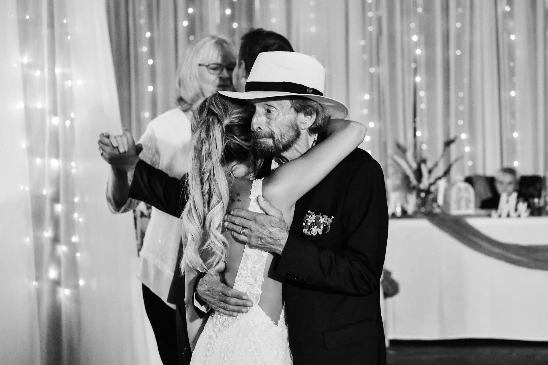 A black and white photo of a bride and groom hugging at their wedding reception.