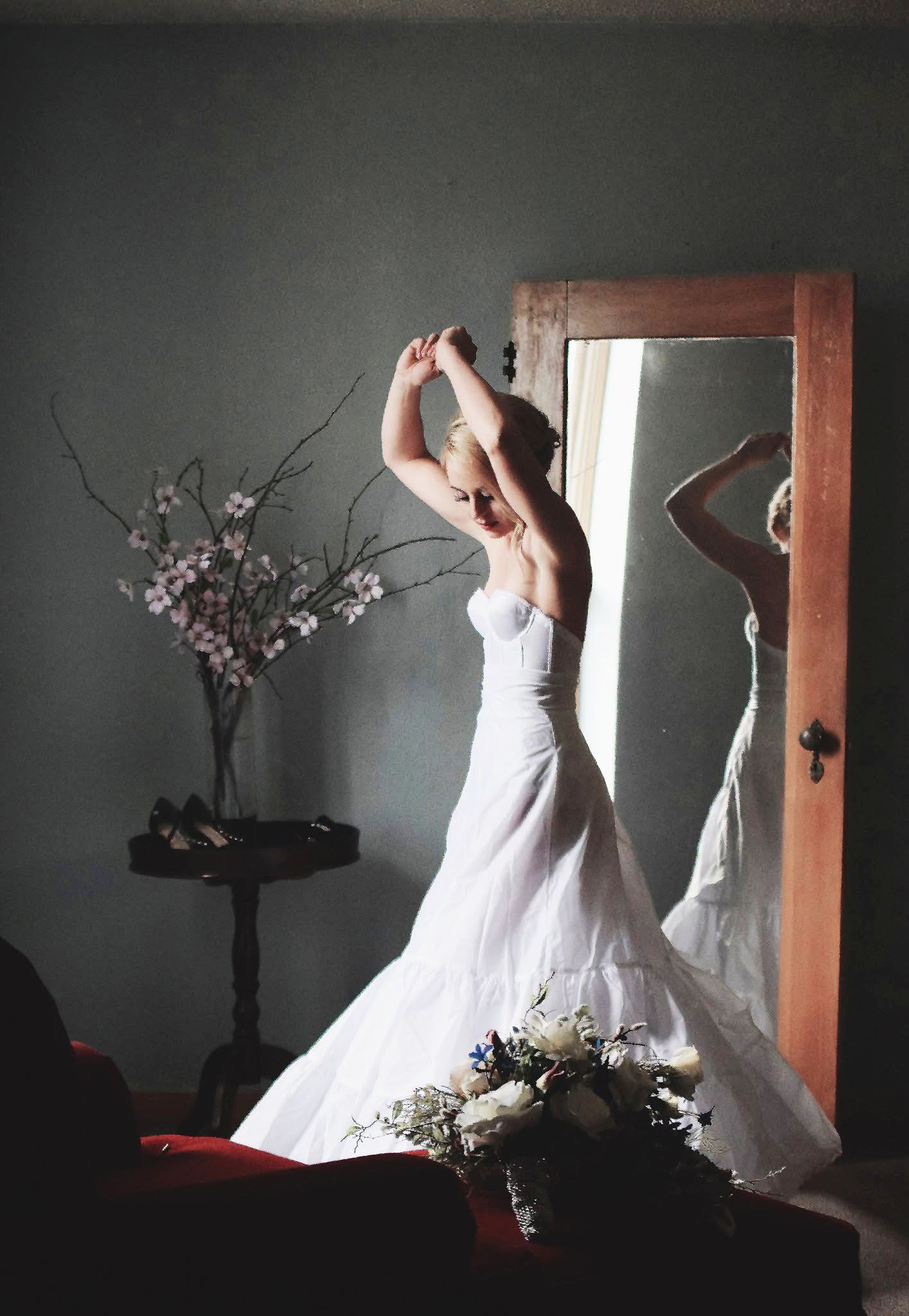 A woman in a white dress is standing in front of a mirror