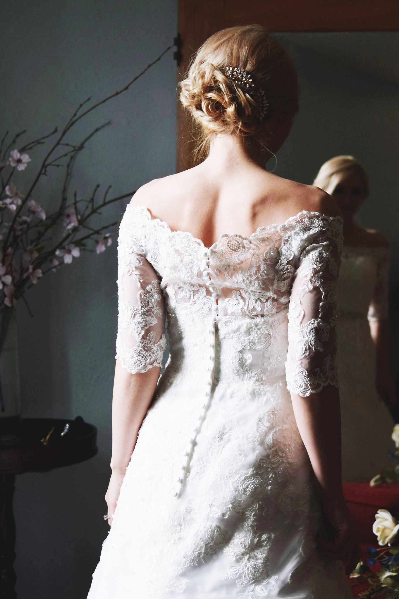A woman in a wedding dress is standing in front of a mirror