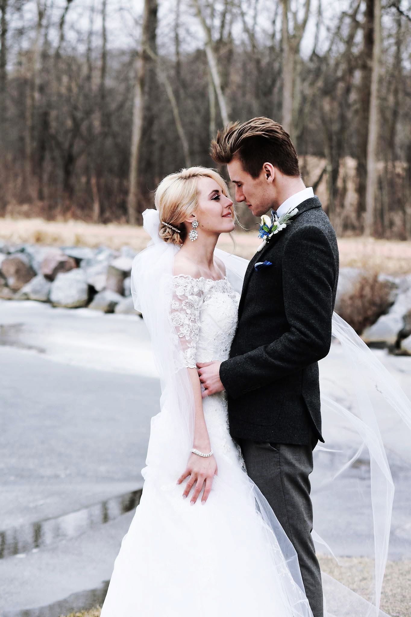 A bride and groom are standing next to each other and looking into each other 's eyes.