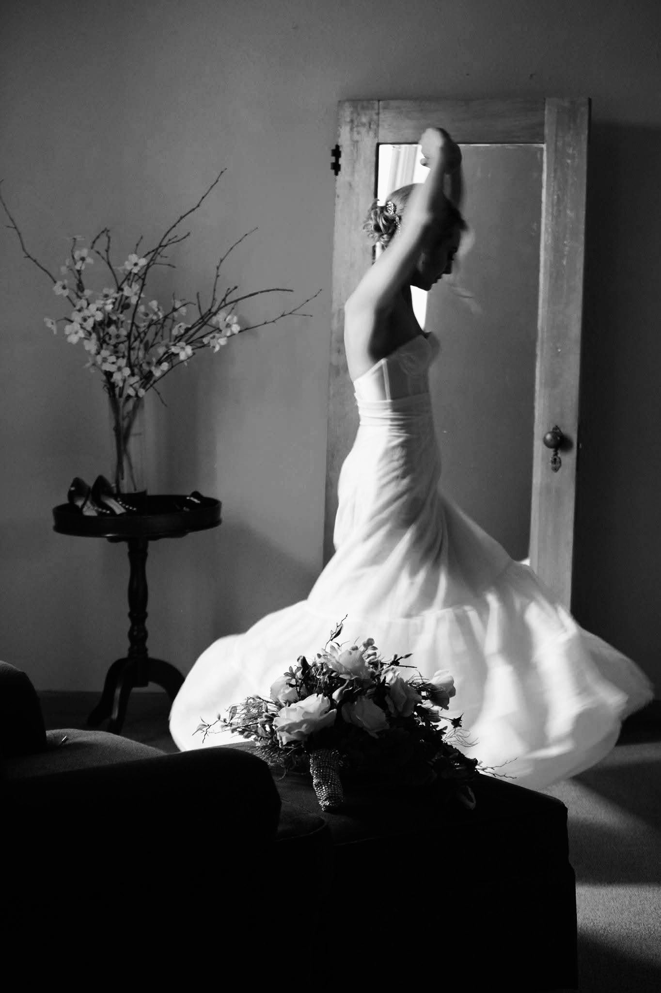 A woman in a wedding dress is standing in front of a mirror.