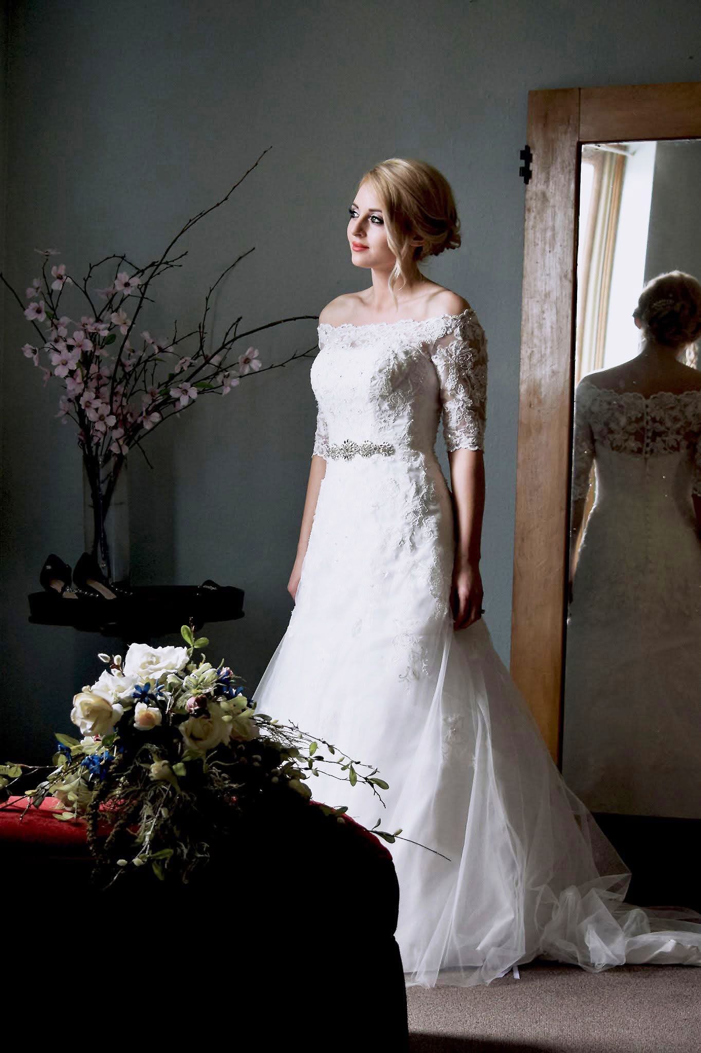 A woman in a wedding dress is standing in front of a mirror.