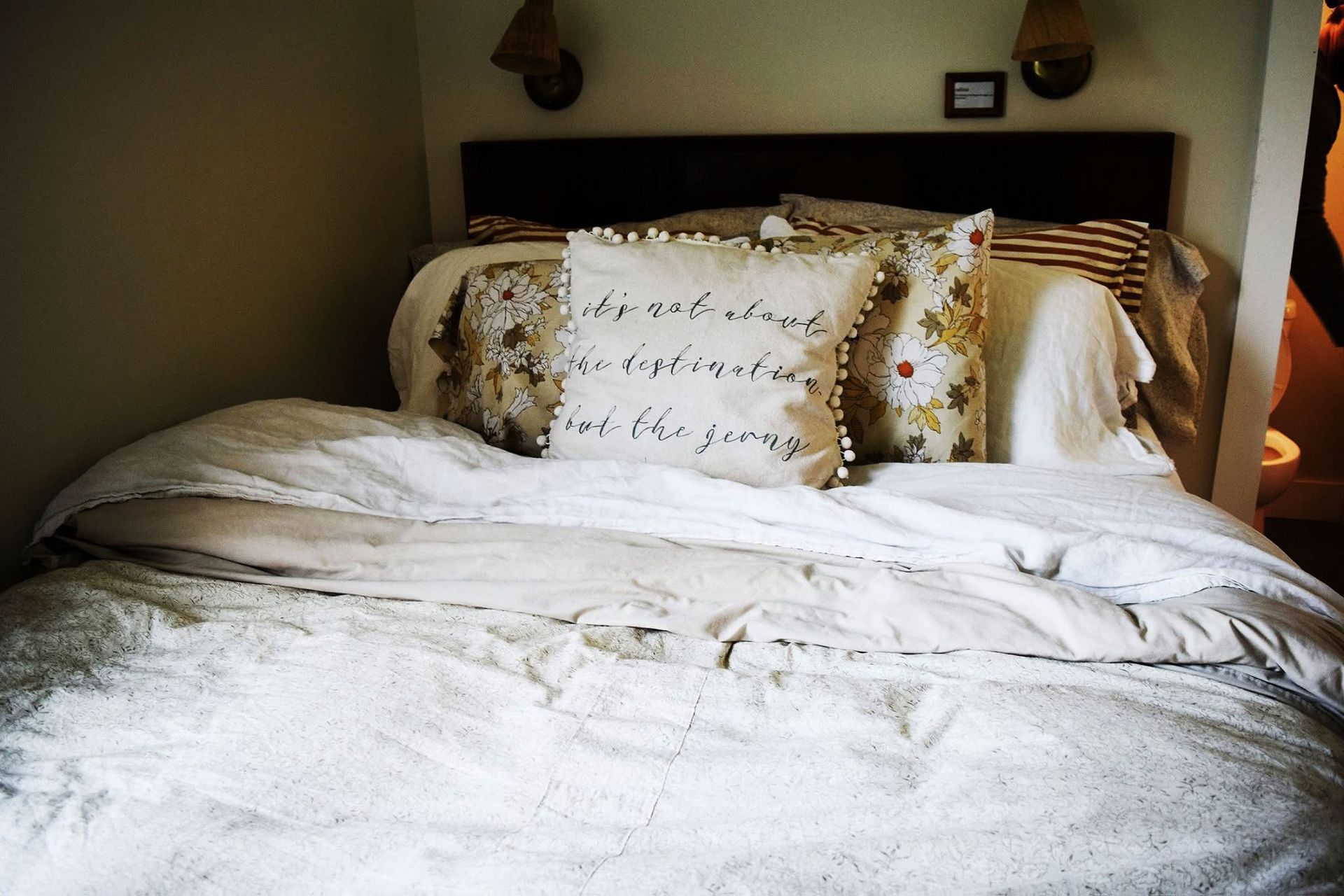 A bed with white sheets and a pillow that says 