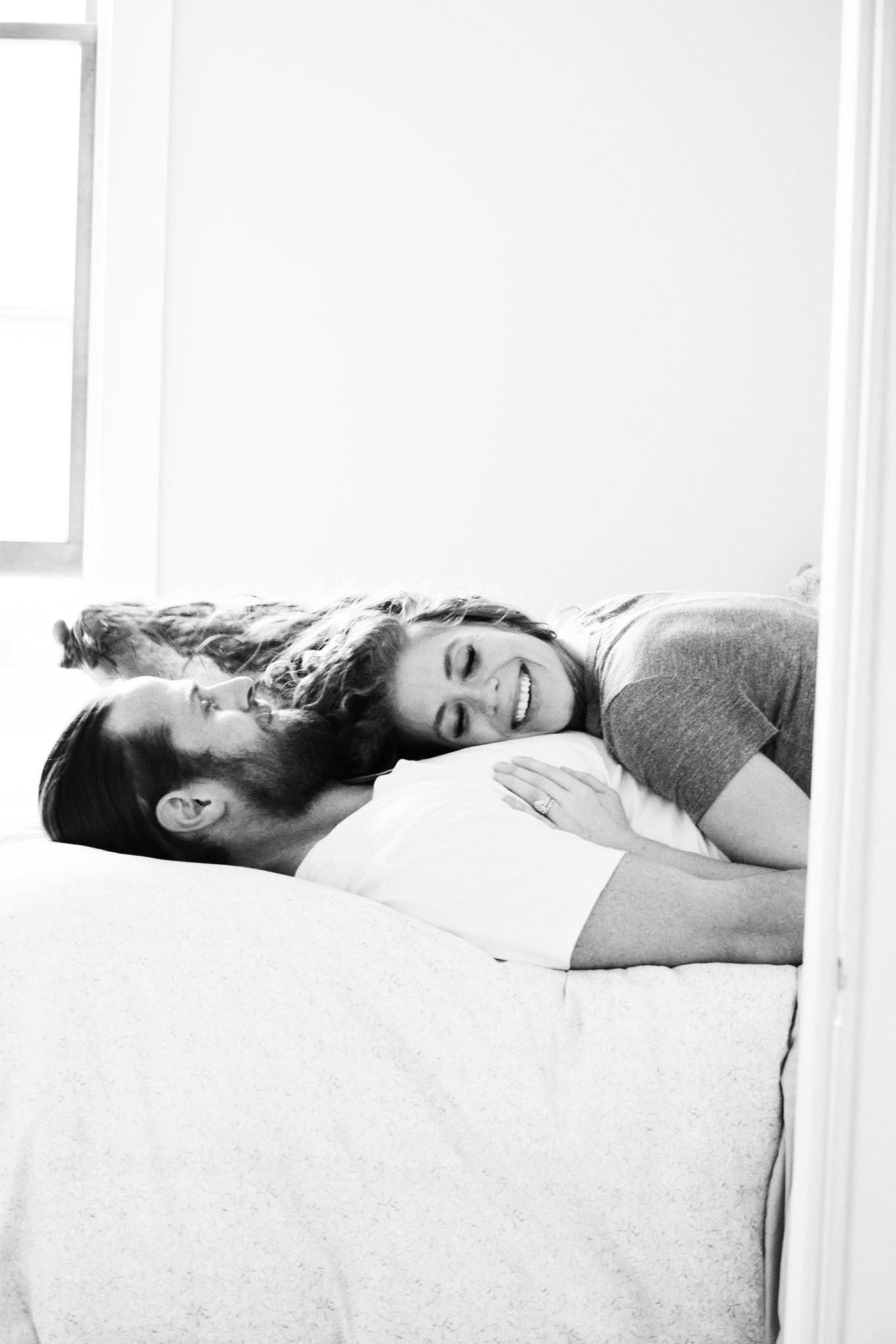 A black and white photo of a man and woman laying on a bed.