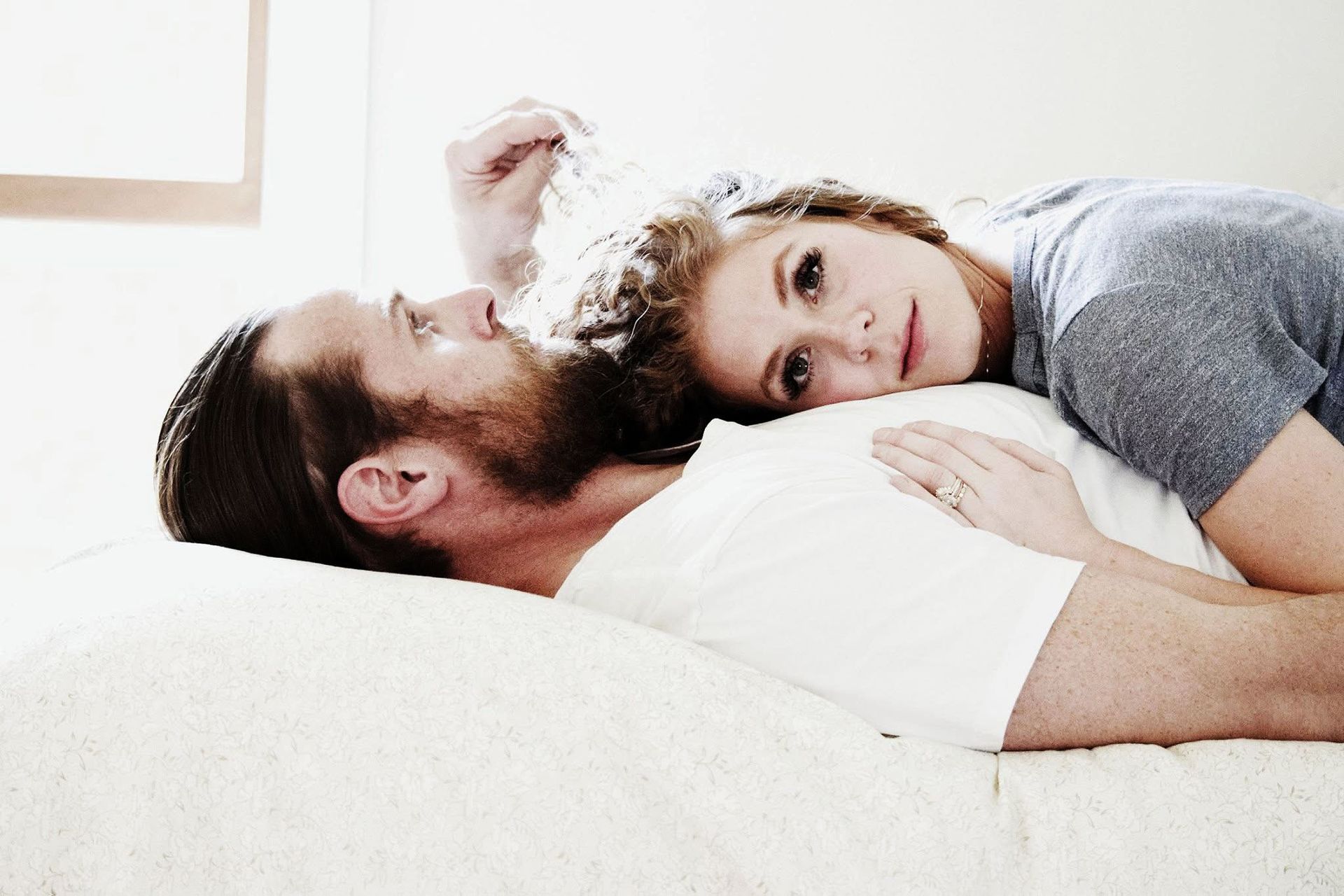 A man and a woman are laying on a bed.