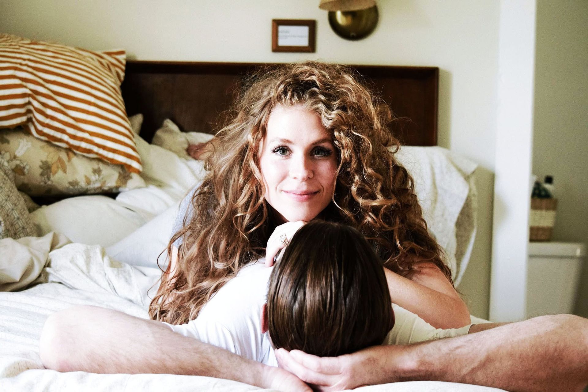 A woman with curly hair is laying on top of a man 's head