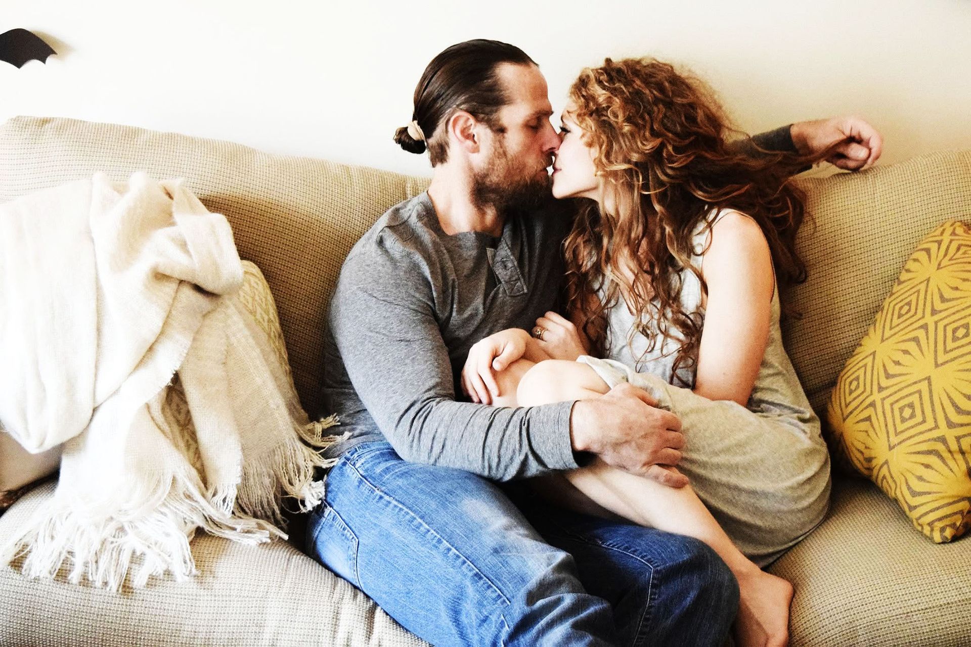 A man and a woman are kissing on a couch.