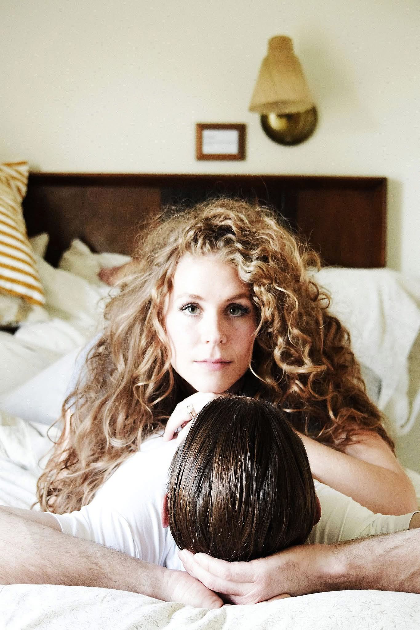 A woman with curly hair is laying on top of a man 's head