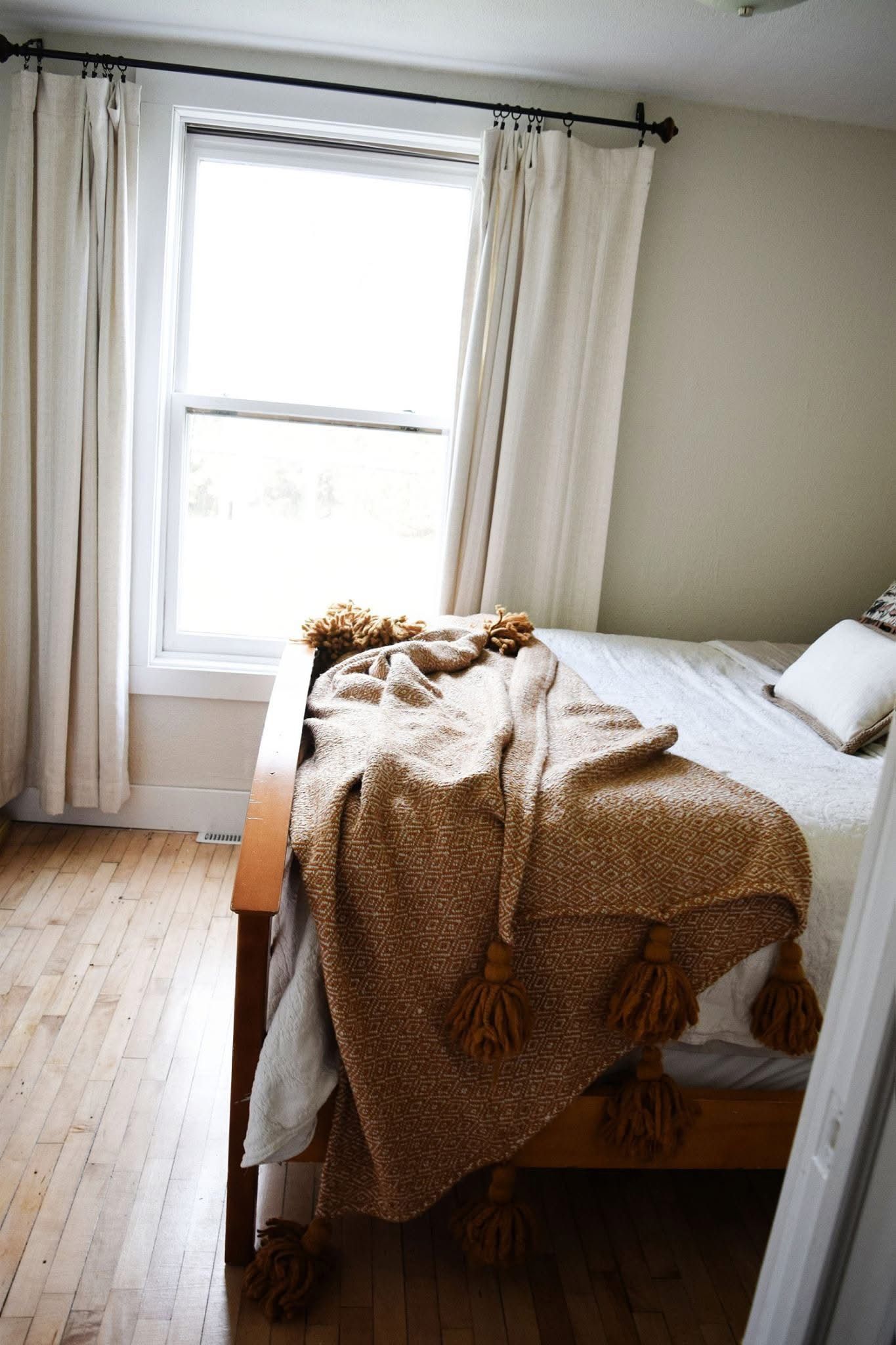 A bed with a blanket on it in a bedroom next to a window.
