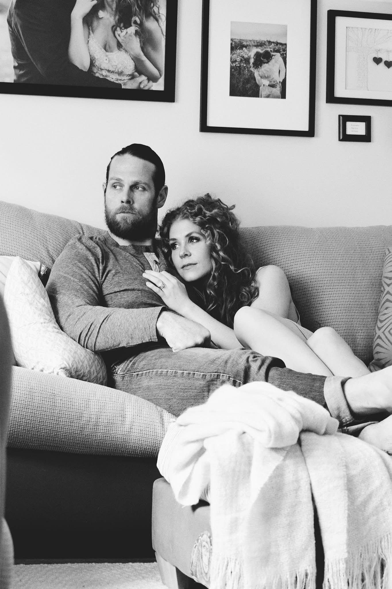 A black and white photo of a man and woman sitting on a couch.