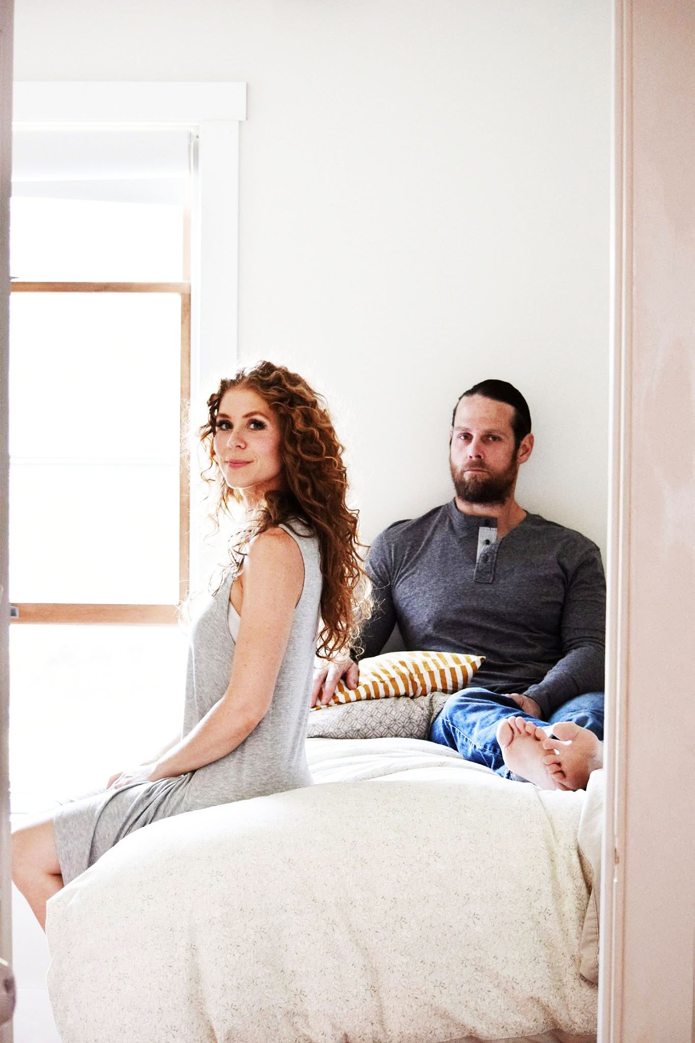 A man and a woman are sitting on a bed.
