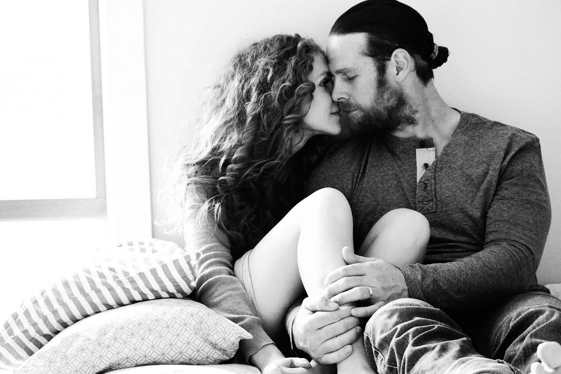 A black and white photo of a man and woman kissing on a couch.