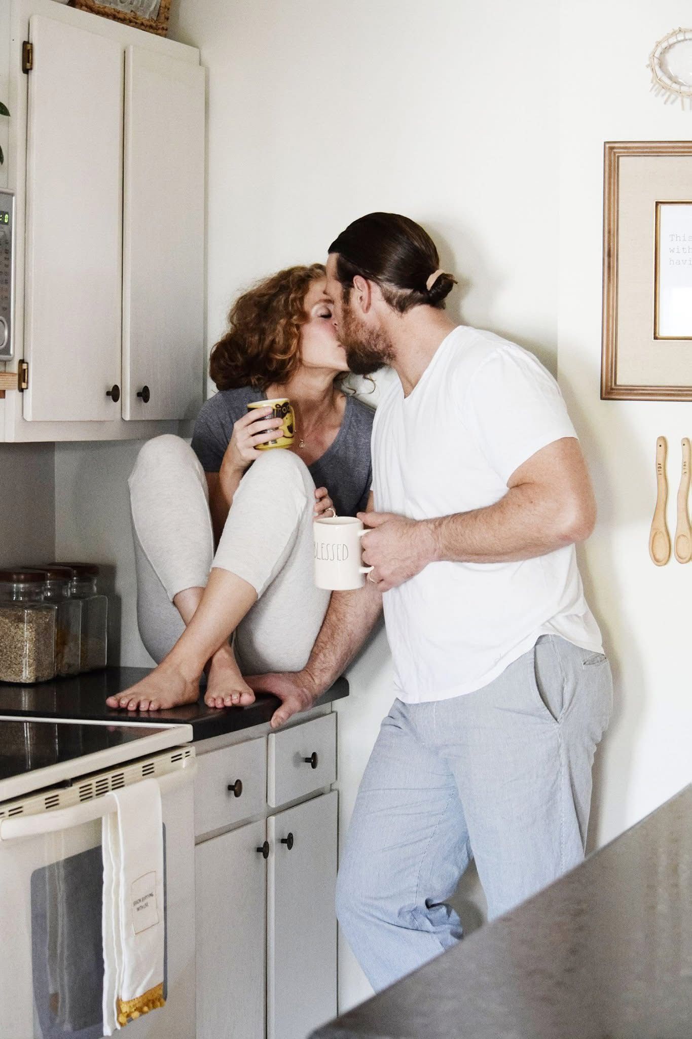 A man and a woman are kissing in a kitchen