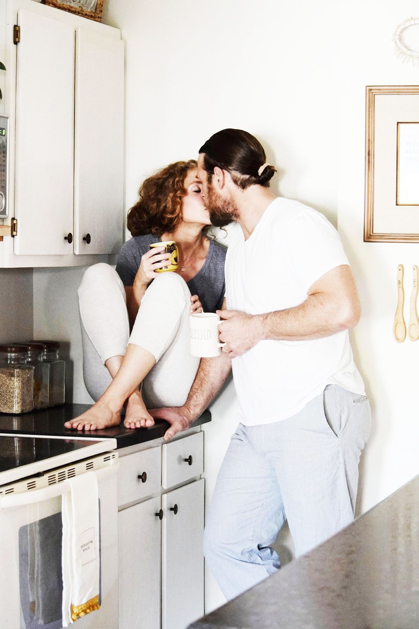 A man and a woman are kissing in a kitchen
