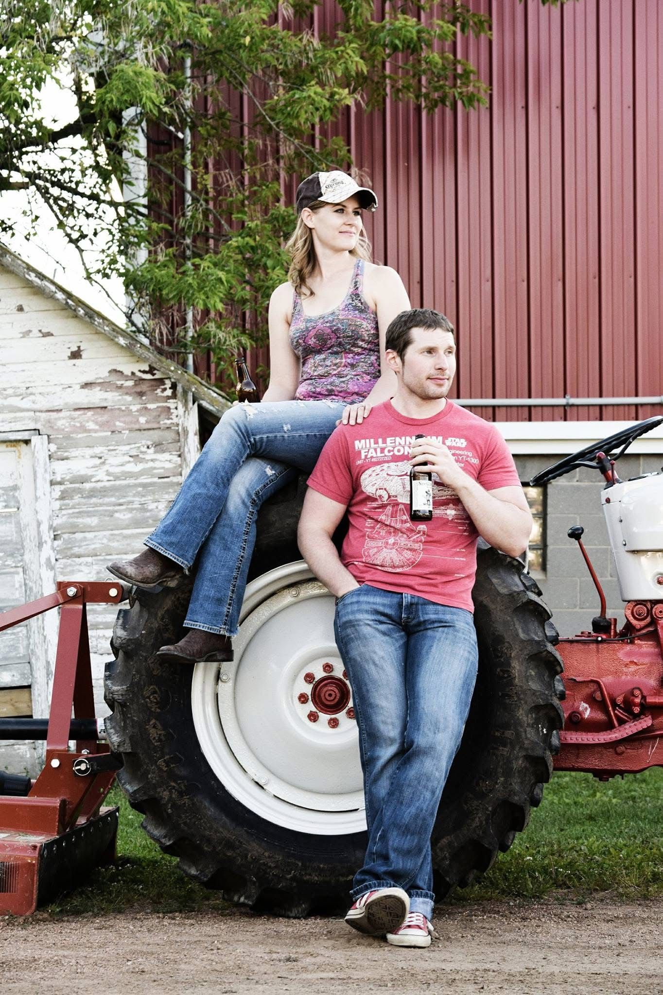 A man and a woman are sitting on a tractor tire.
