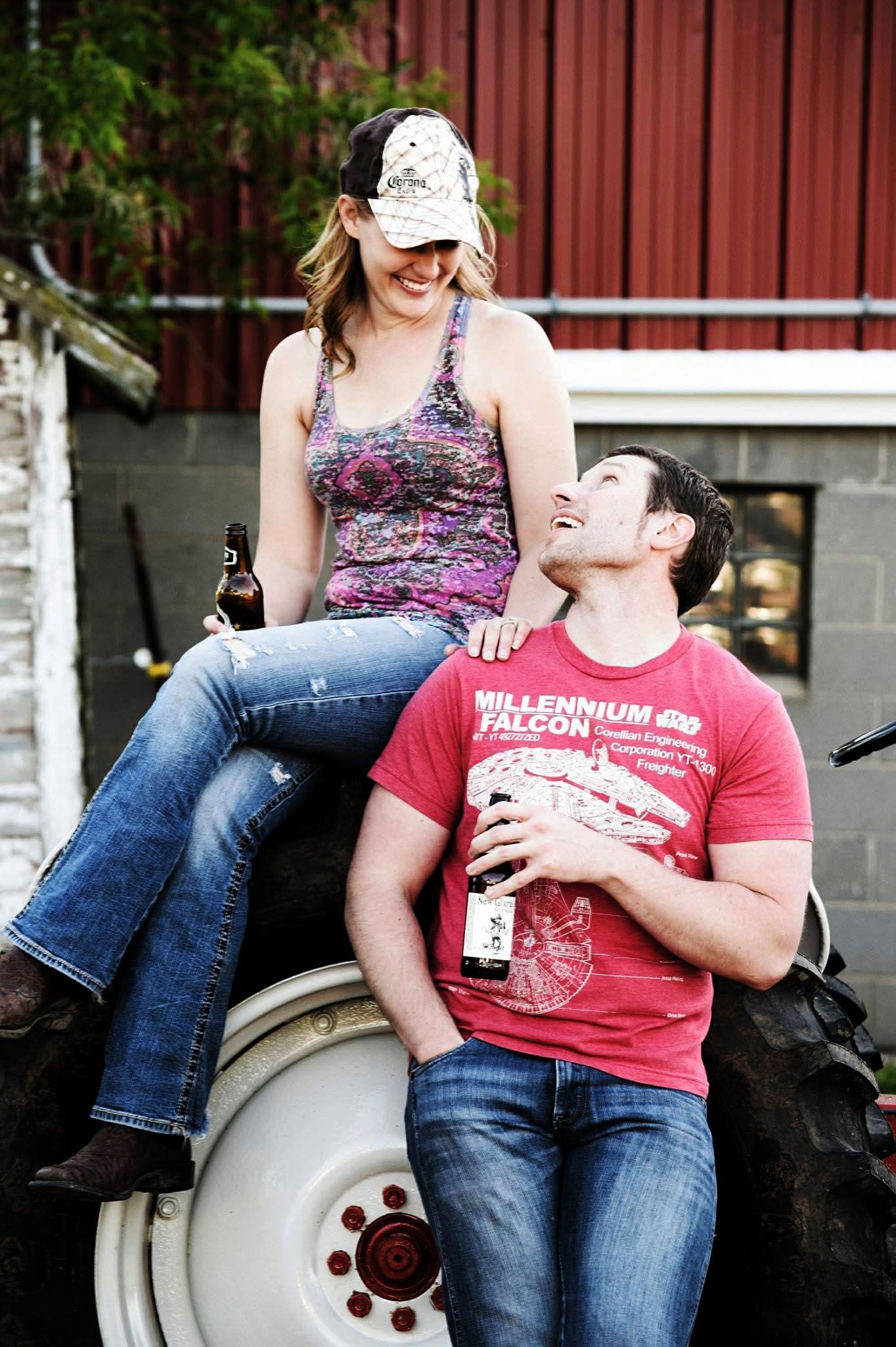 A woman is sitting on a man 's lap on a tractor.
