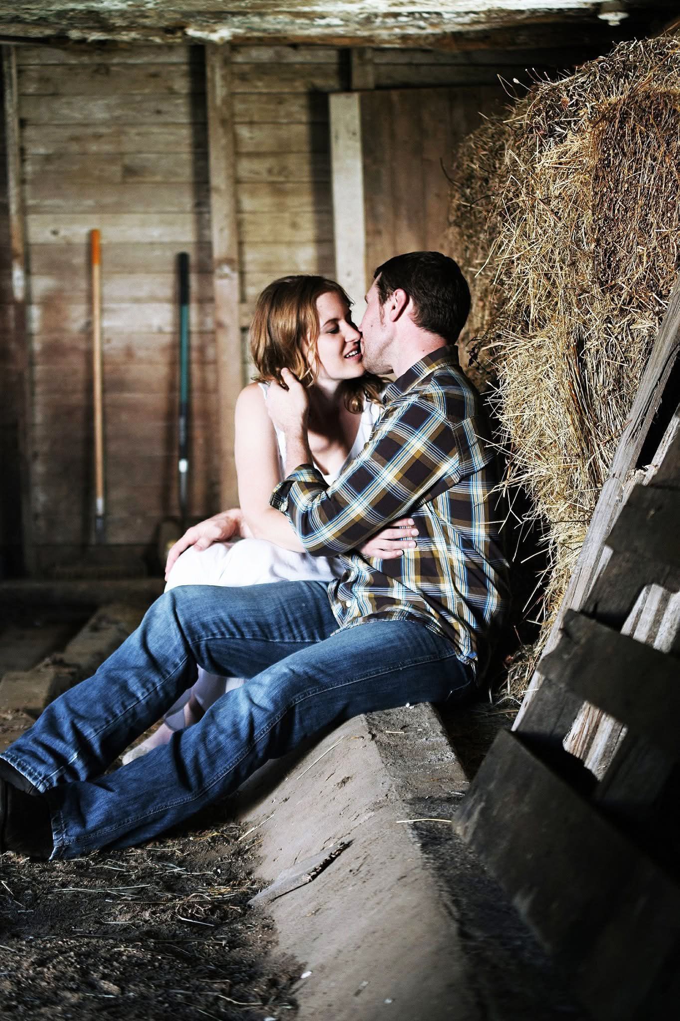 A man and a woman are sitting next to each other in a barn.
