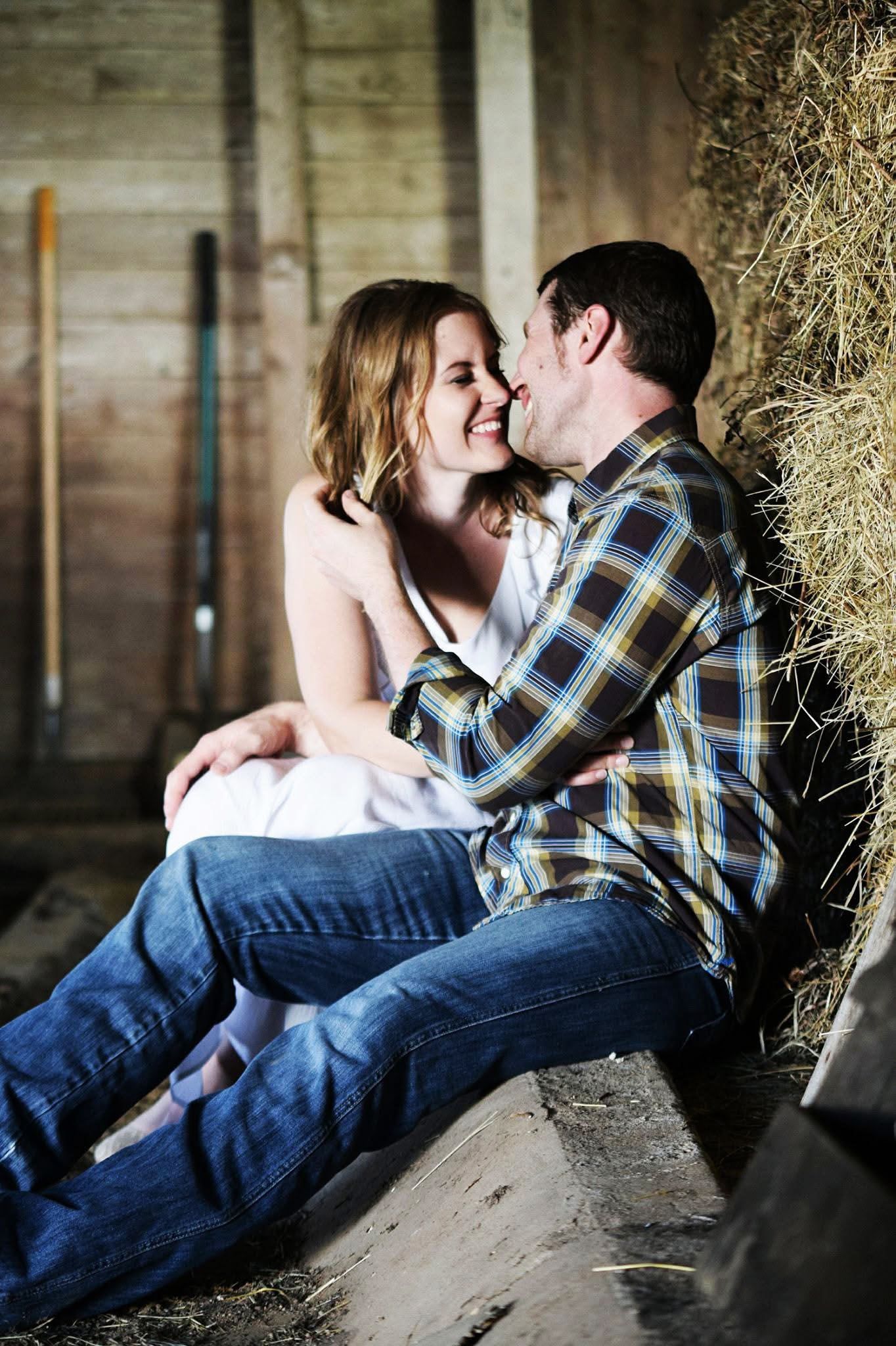 A man and a woman are sitting next to each other in a barn.