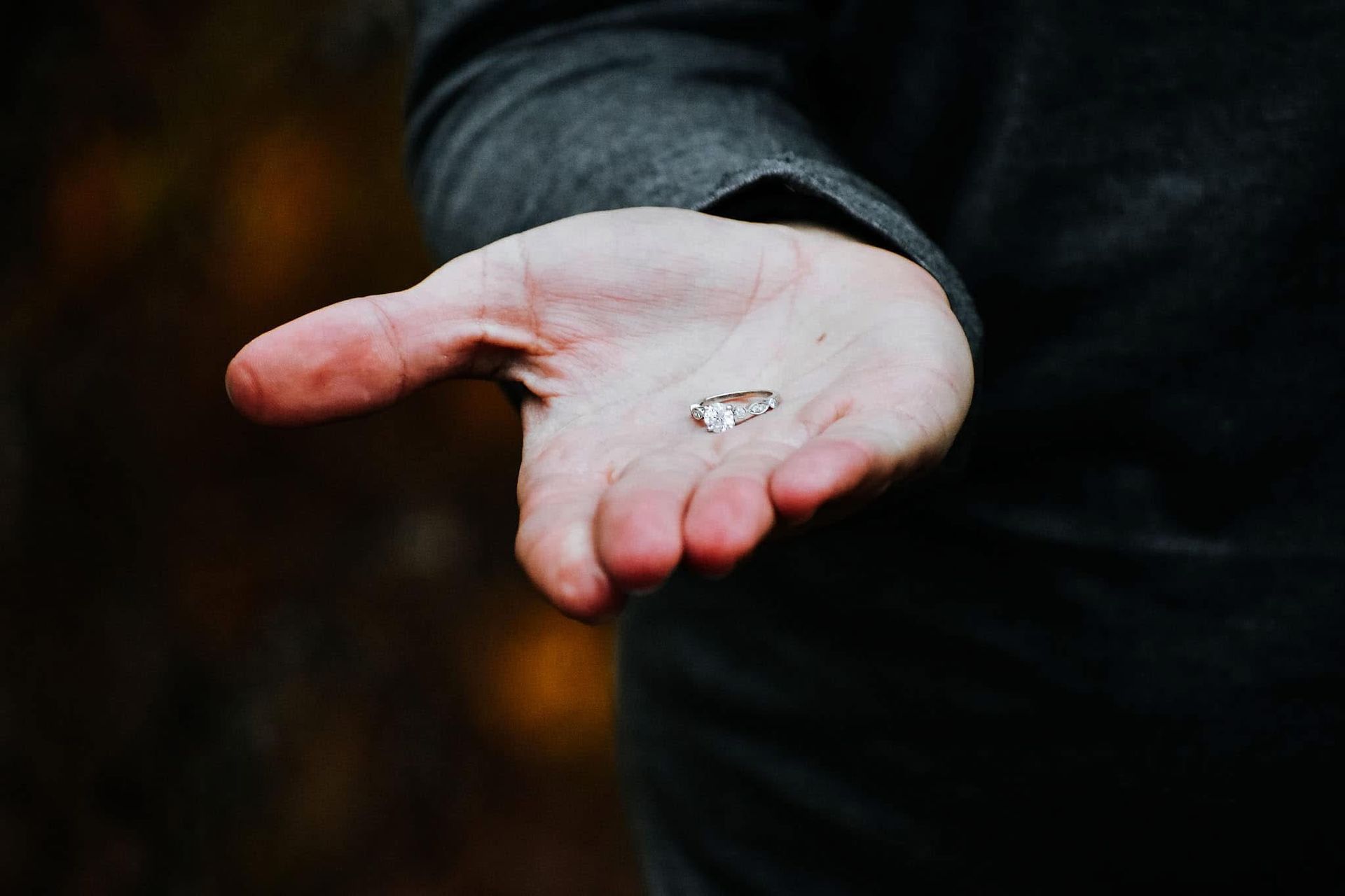A person is holding a pair of wedding rings in their hand.
