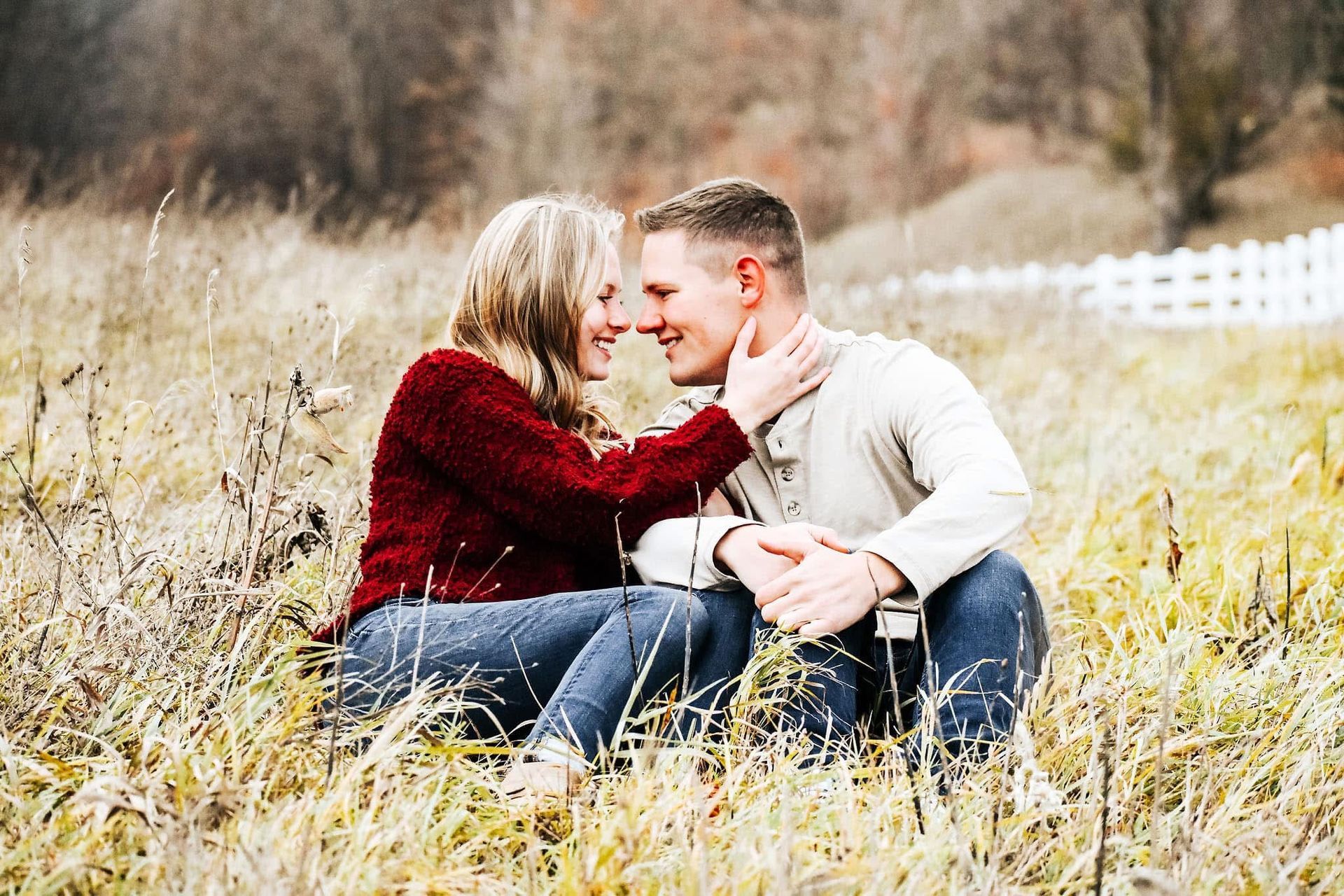 A man and a woman are sitting in a field looking at each other.