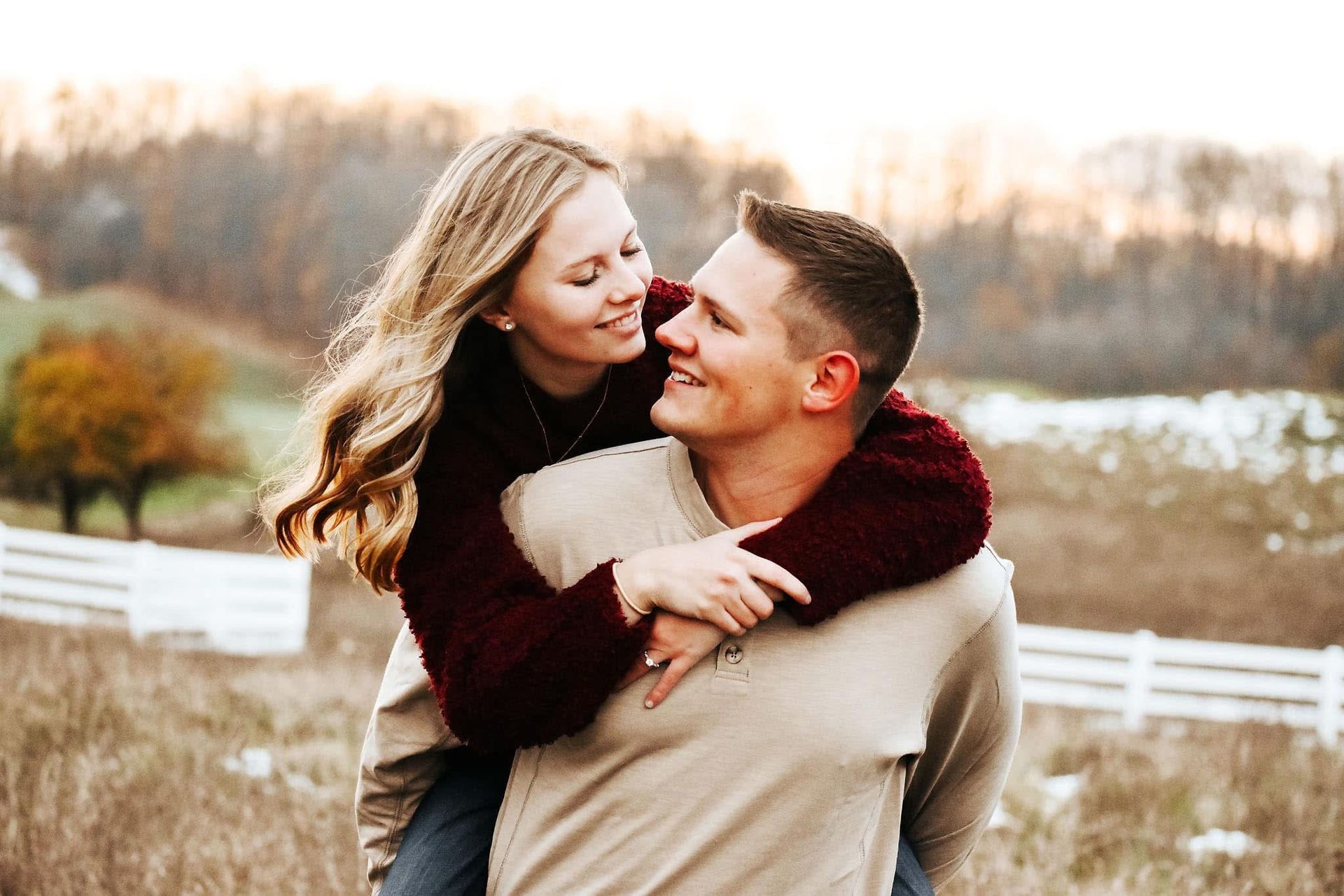 A man is carrying a woman on his back in a field.