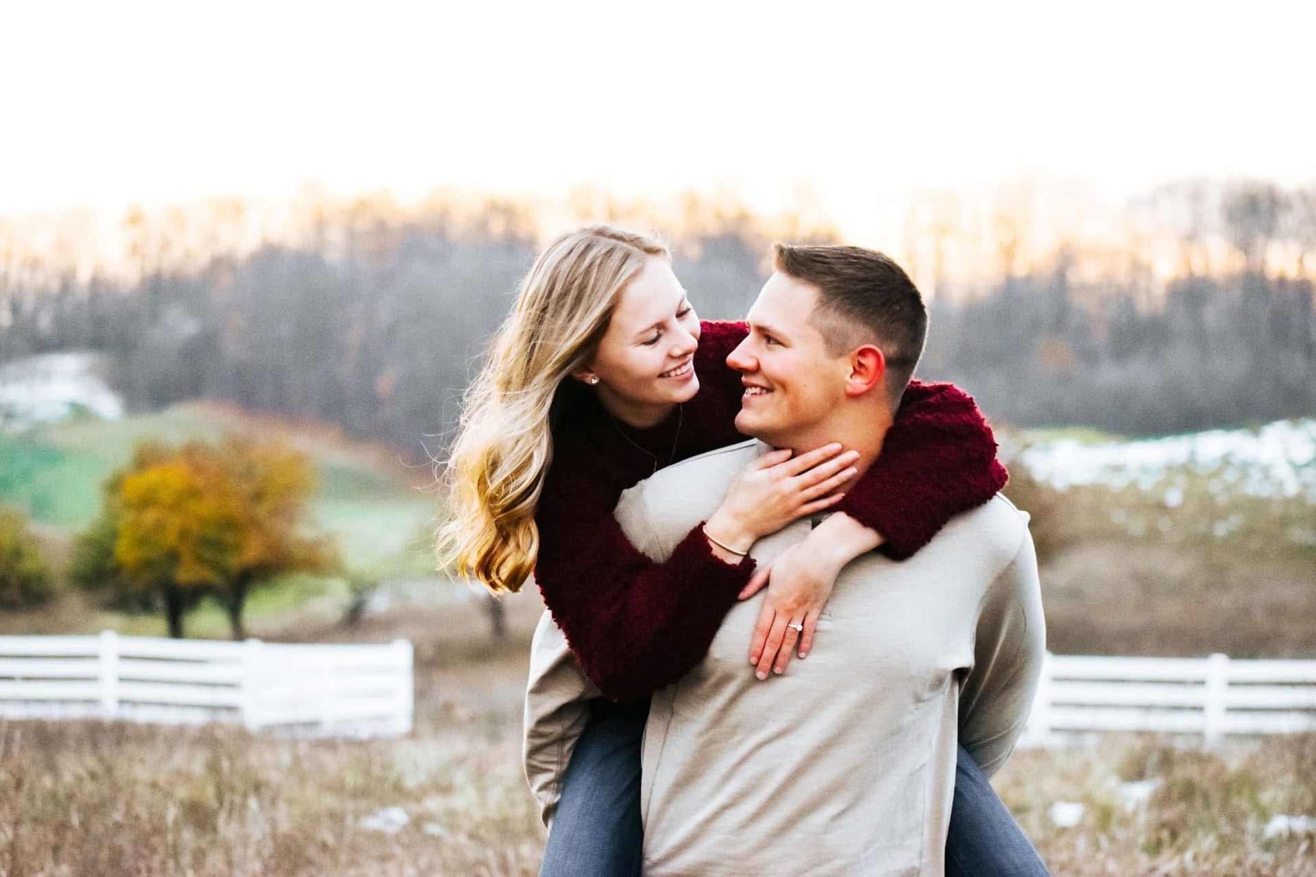 A man is carrying a woman on his back in a field.
