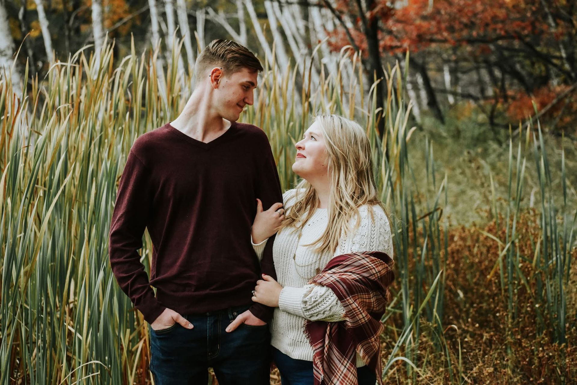 A man and a woman are standing in a field looking at each other.