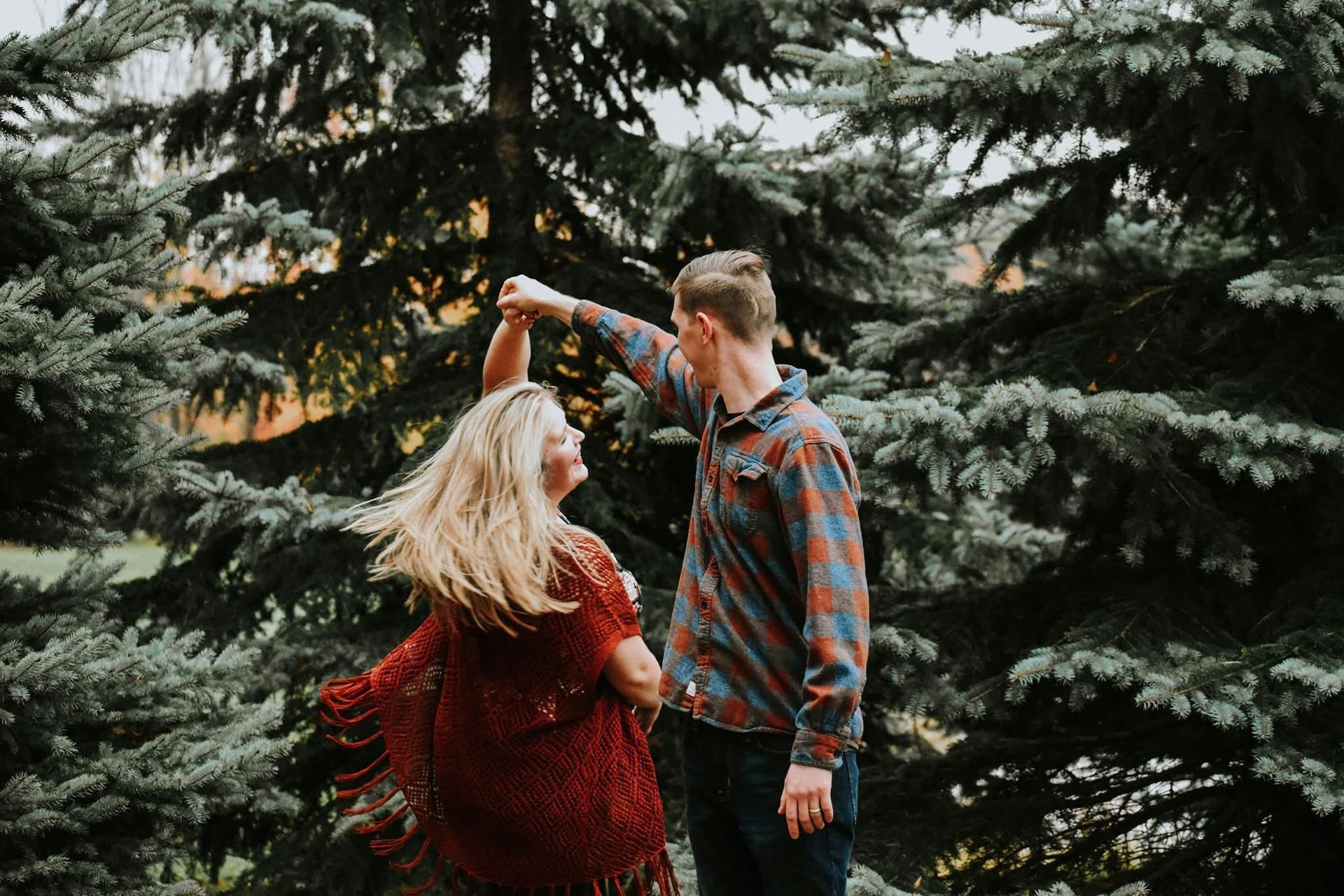 A man and a woman are dancing in the woods.